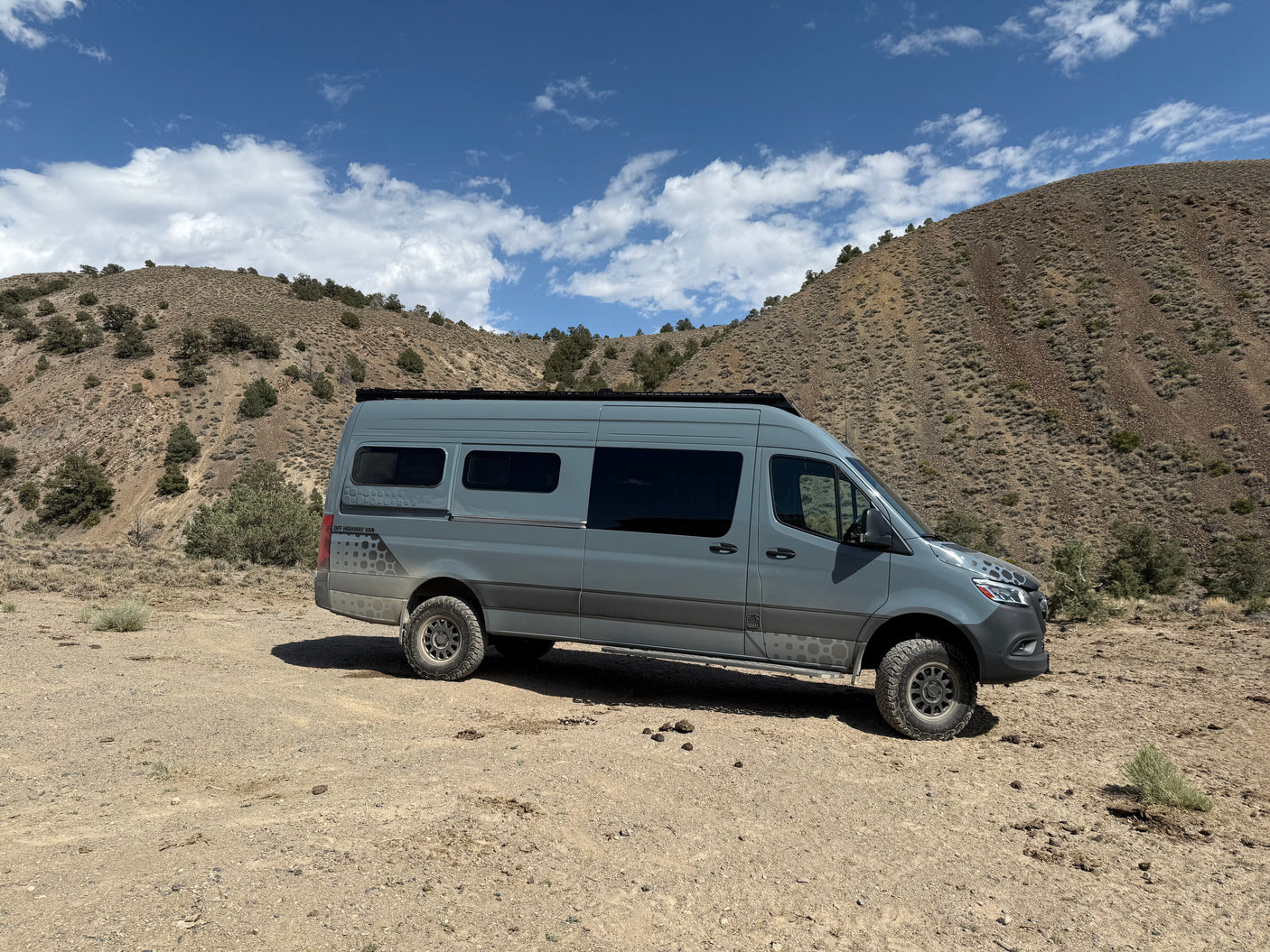 Explore the wilderness with this rugged Sprinter adventure rv rental van, parked in arid, mountainous terrain.