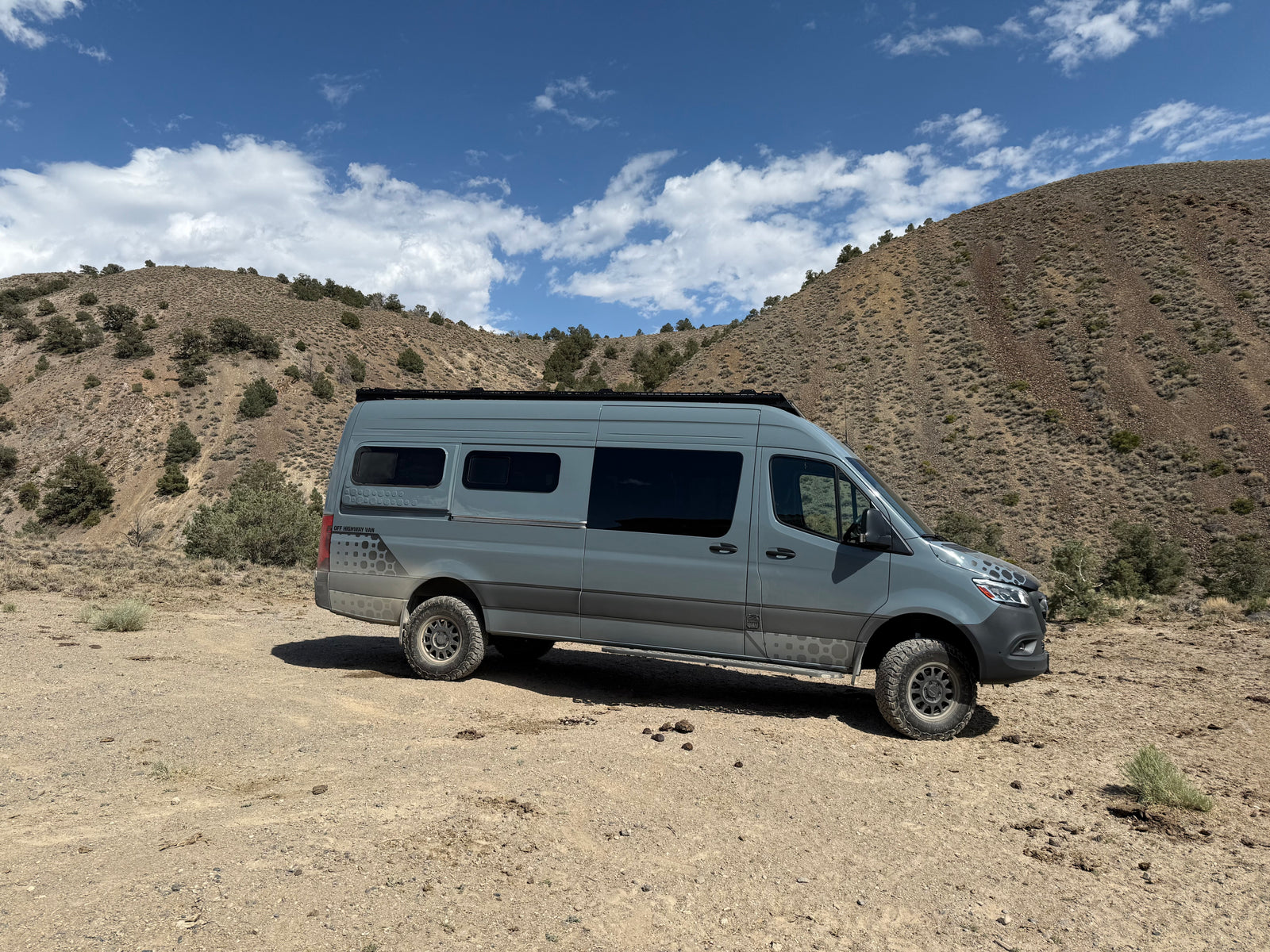 Explore the wilderness with this rugged Sprinter adventure rv rental van, parked in arid, mountainous terrain.
