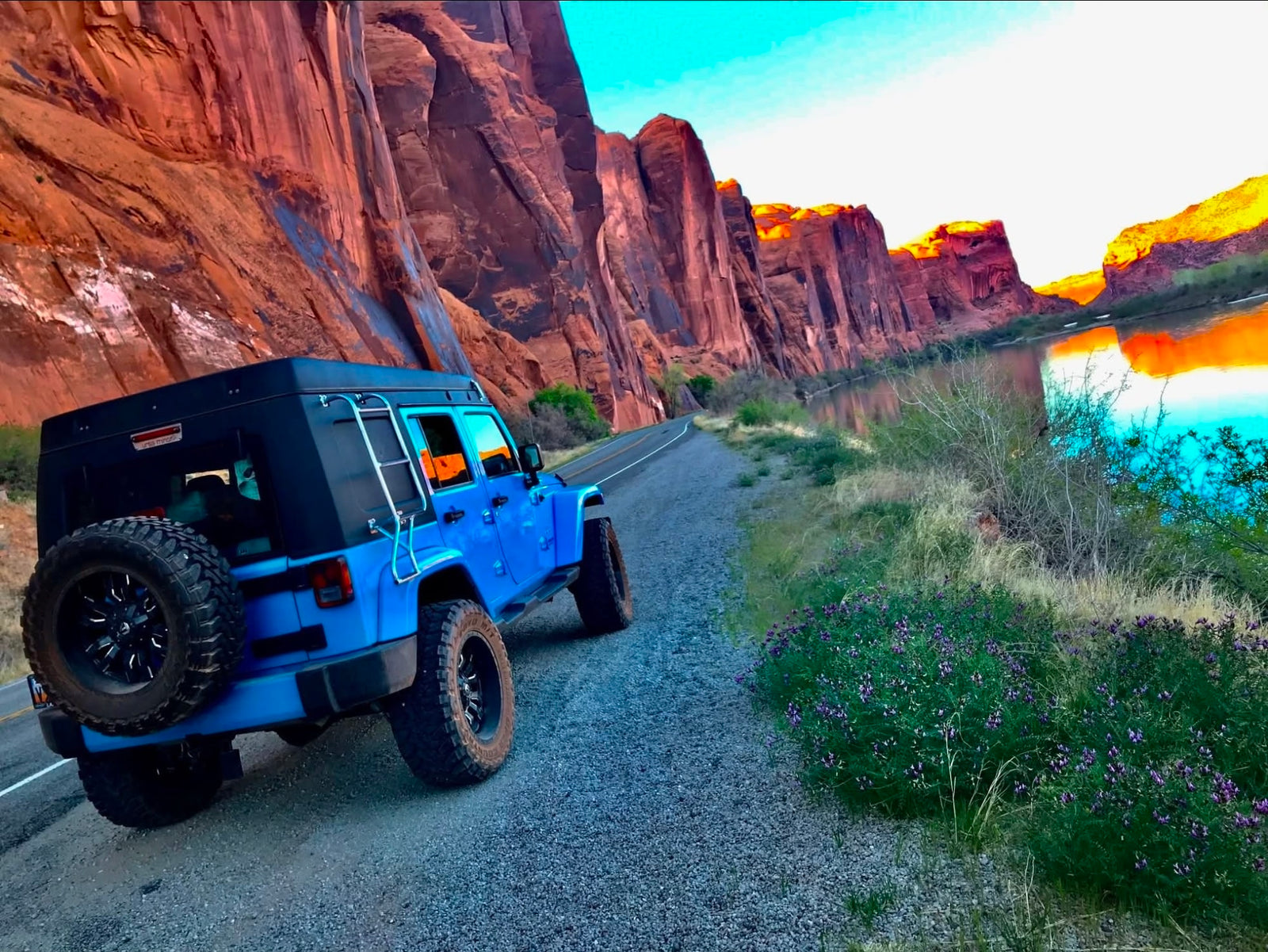 rests among towering red rock formations in a vast desert landscape.|A blue Jeep