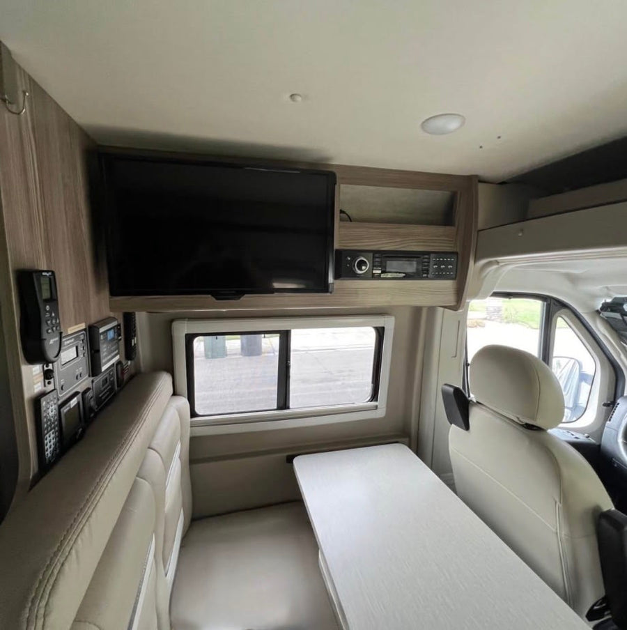 and sunshade.|Stunning RV rental view: Desert landscape at sunset with sky contrails mirrored on the vehicle's solar panel.|Comfortable rv rental interior: cream seating