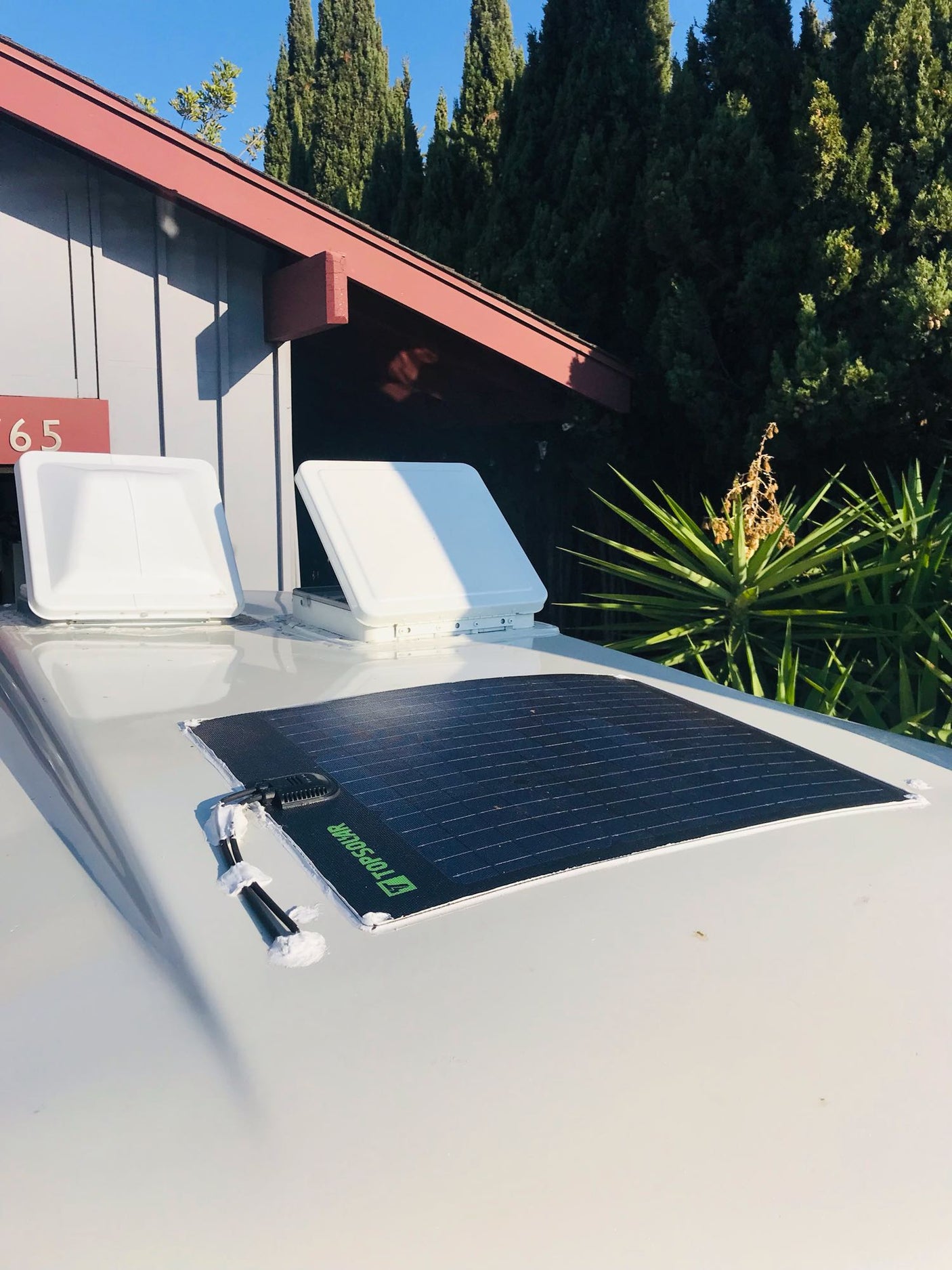 RV rental's roof with two white vents and a TOPSOLAR flexible panel. Perfect for camper off-grid power.