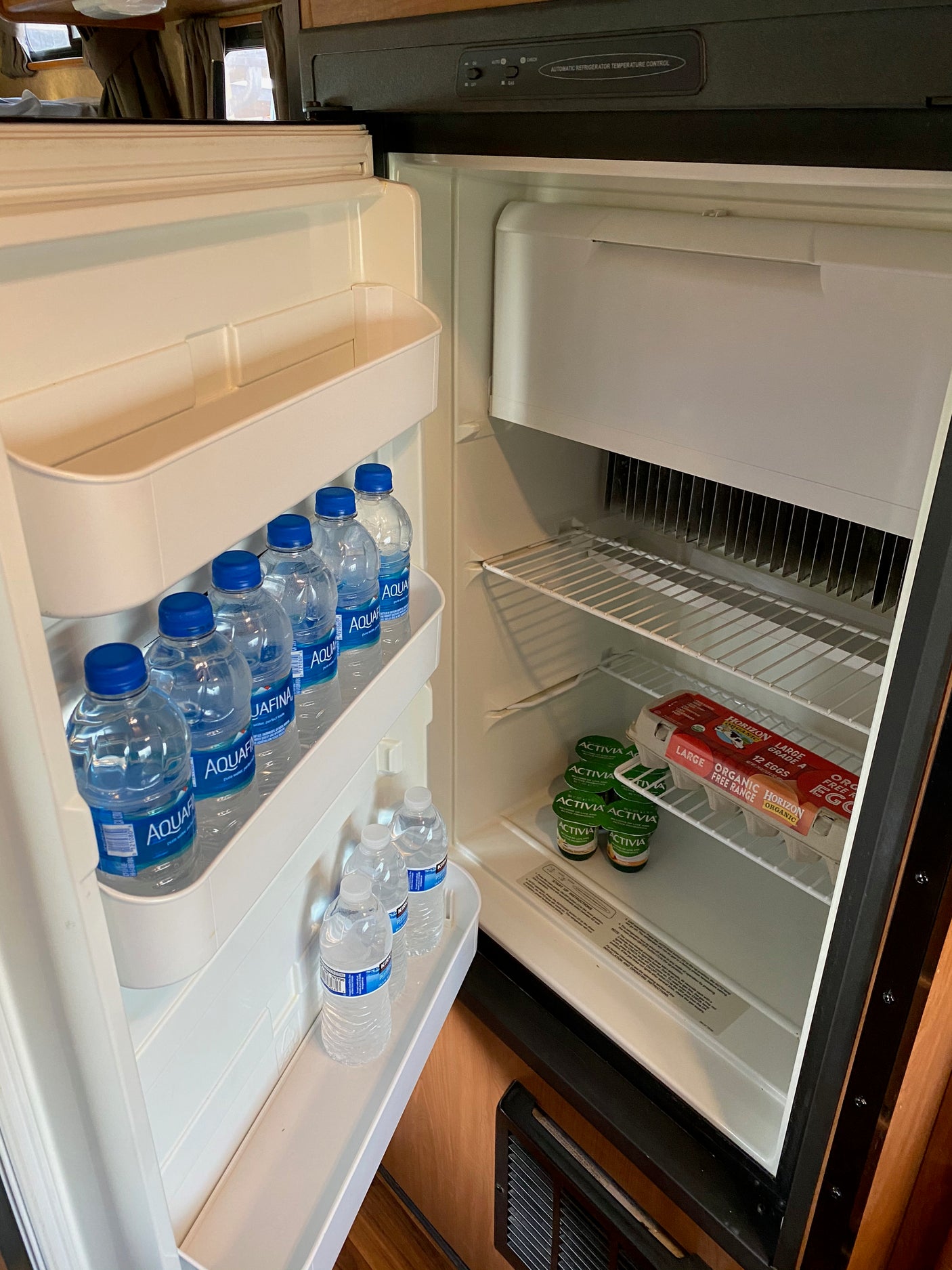 Stocked RV rental refrigerator with bottled water, yogurts, and eggs, ready for your travels.