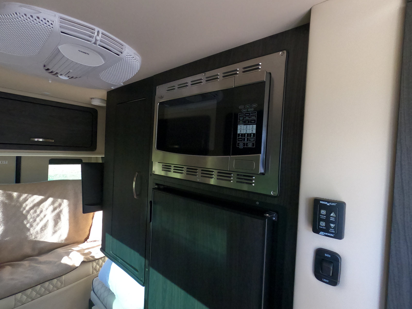 An RV rental interior showing a Dometic AC, microwave, fridge, and MaxxAir controls for comfort on the road.