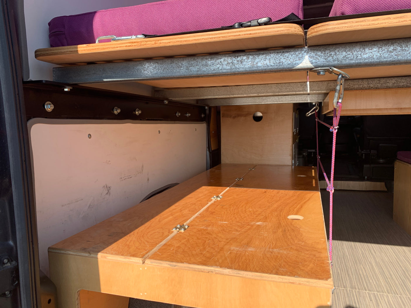 Inside an RV rental: a flexible bunk bed and seating area with custom wooden construction for comfort & storage.