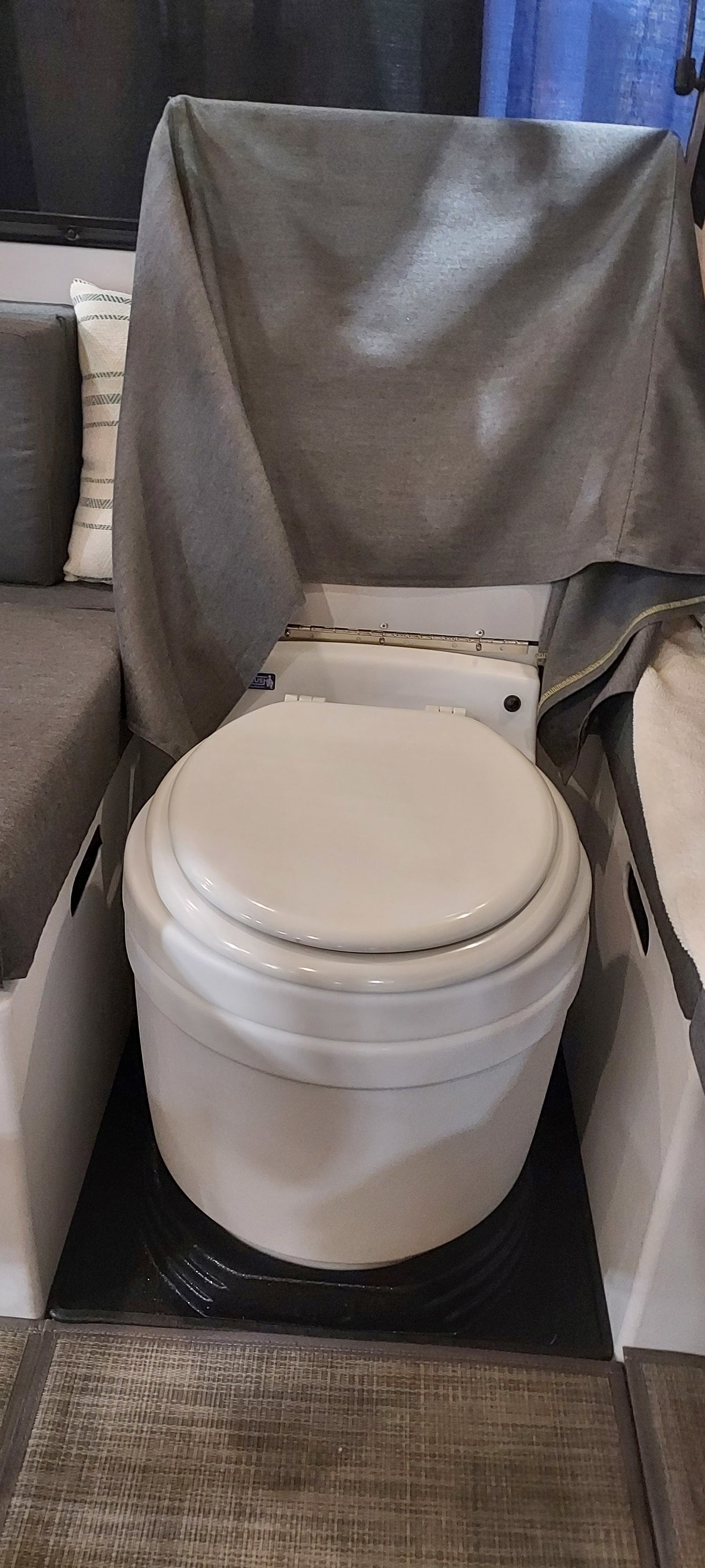 This RV rental features a compact toilet with a grey privacy curtain, located next to seating. Ideal for camper living.