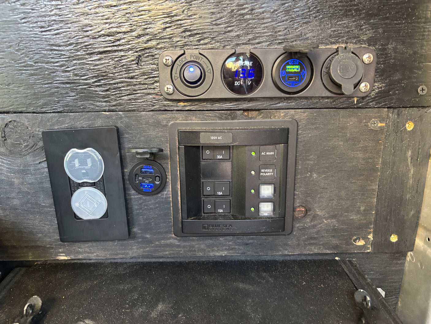 RV rental: Electrical control panel with AC/DC power outlets, USB charging, voltmeter (13.6V), and circuit breakers.