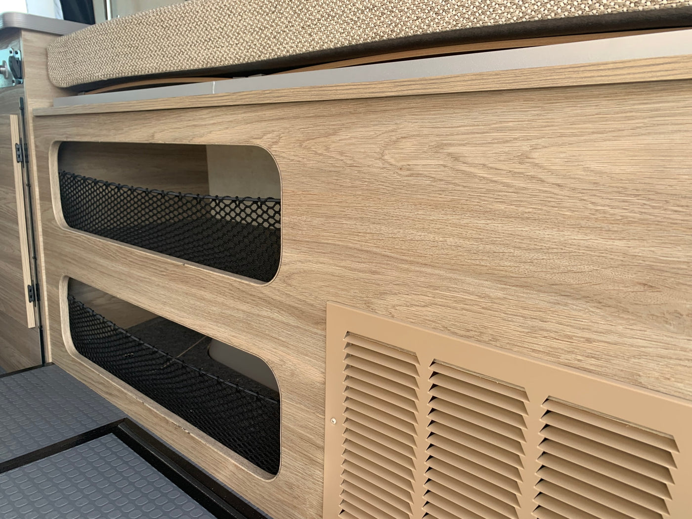 revealing a cozy interior with bed & utility panel. Ideal for an RV rental adventure.|Inside an RV rental: rear view of the living area with light wood cabinetry — photo 8