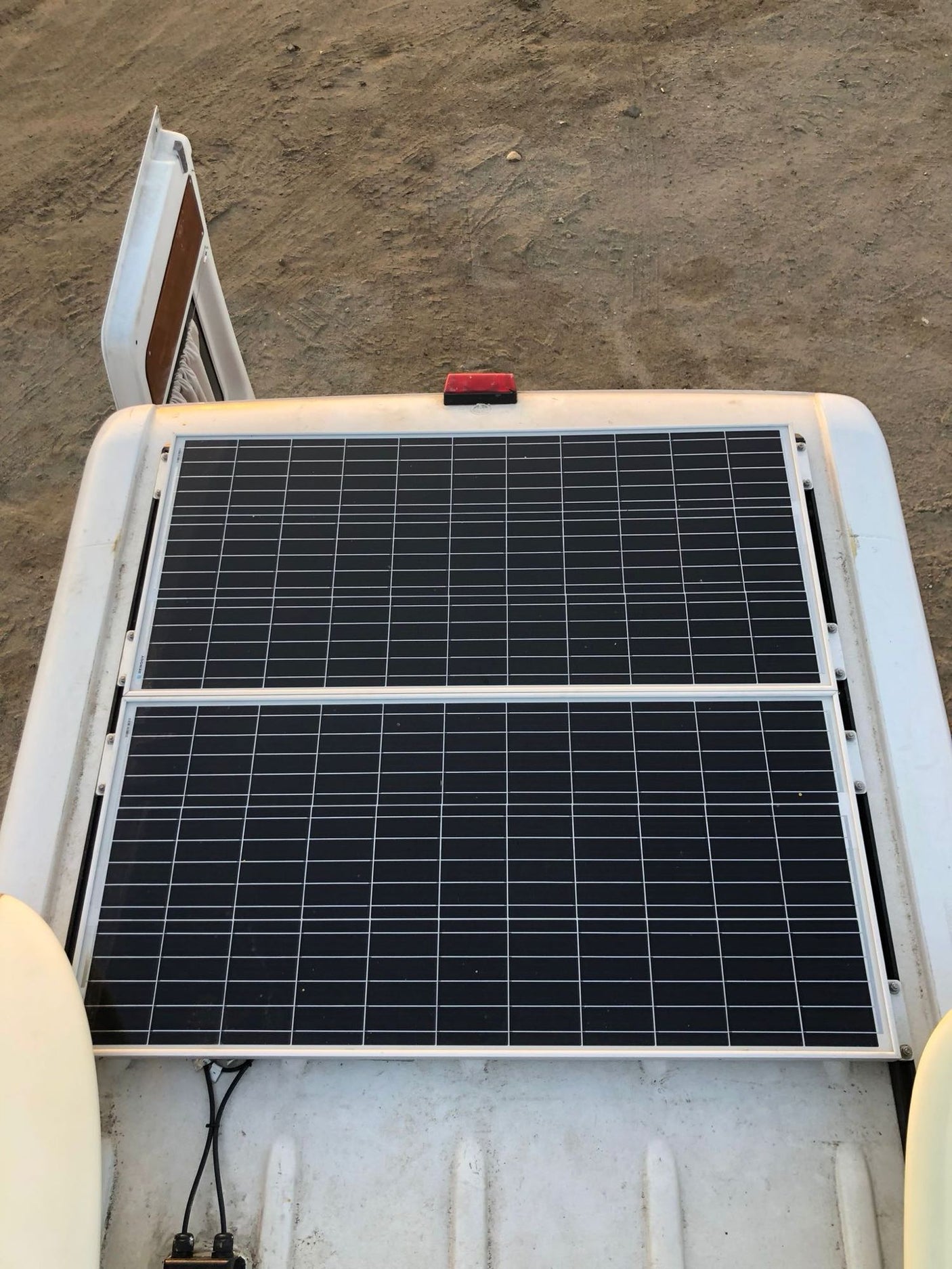 Top view of an RV rental showing two black solar panels mounted on its white roof, providing off-grid power.