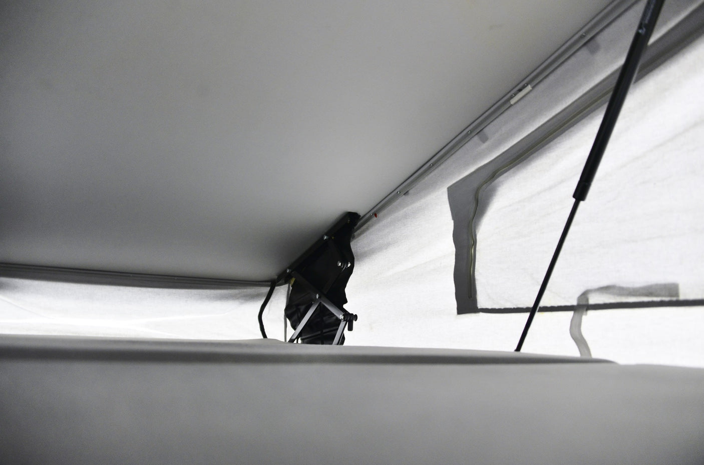 RV rental pop-top interior showing raised roof, black lift mechanism, and light canvas walls. Offers comfortable headroom.