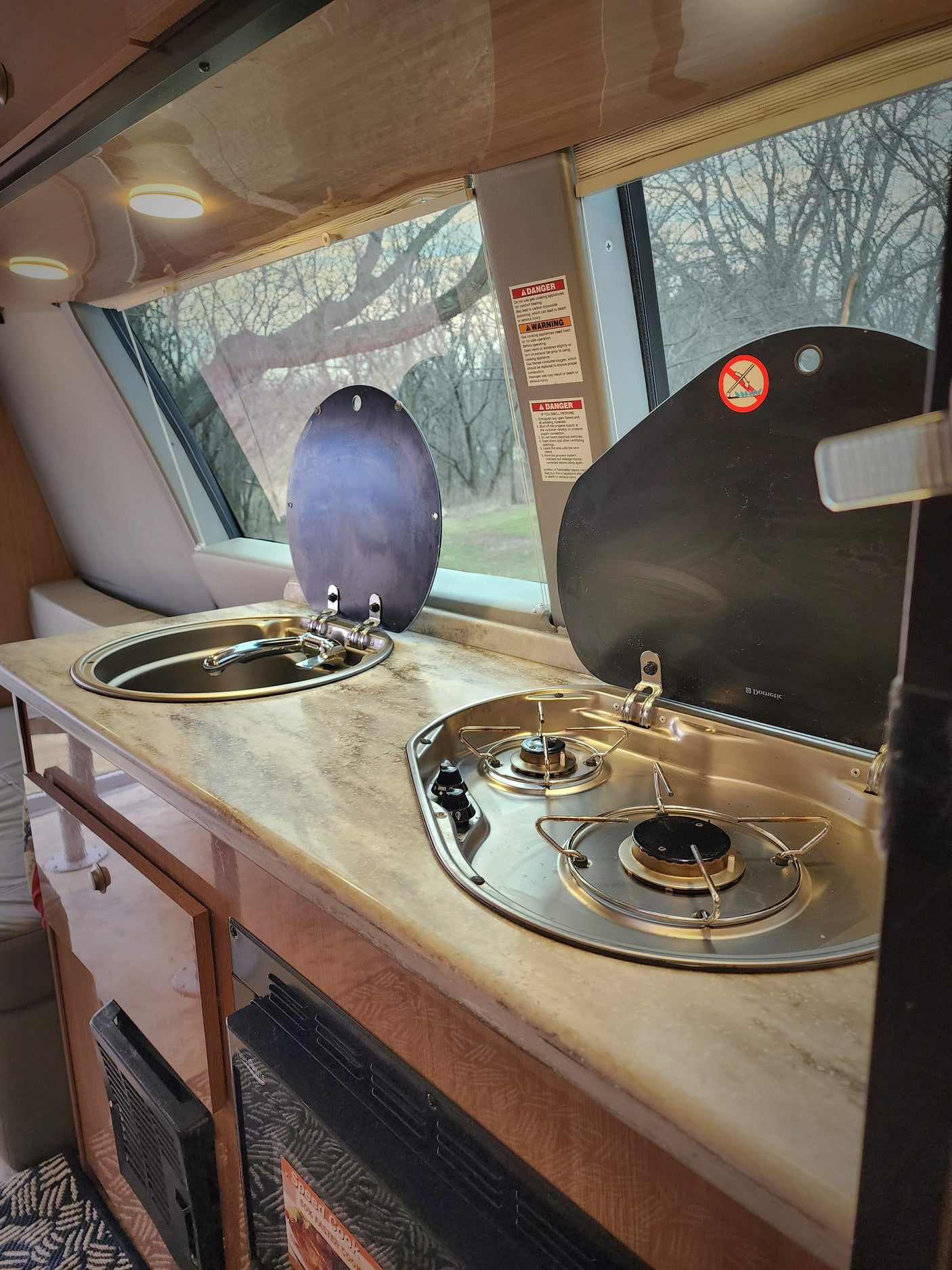 This RV rental kitchen features a stainless steel sink and a Dometic two-burner gas stove for cooking on the road.