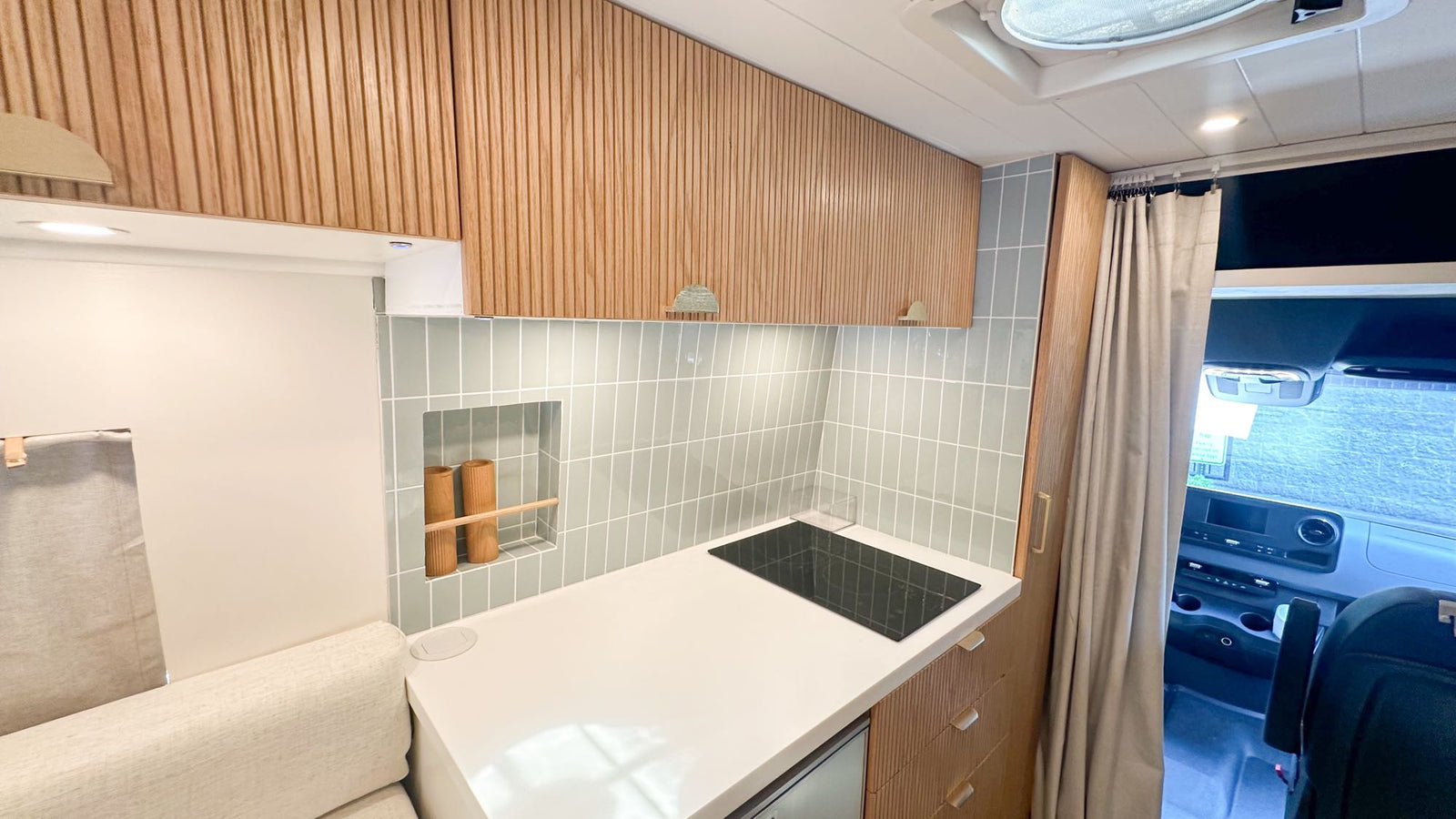 wooden cabinets & table are visible.|White Mercedes Sprinter RV rental van with roof rack & ladder