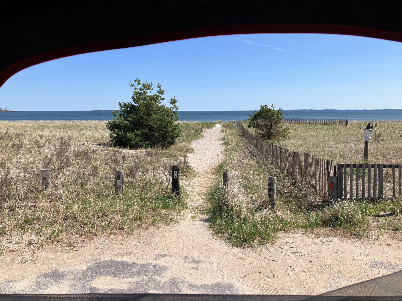 Beach access from an RV rental: a sandy path through dunes to the clear blue ocean under a bright sky.