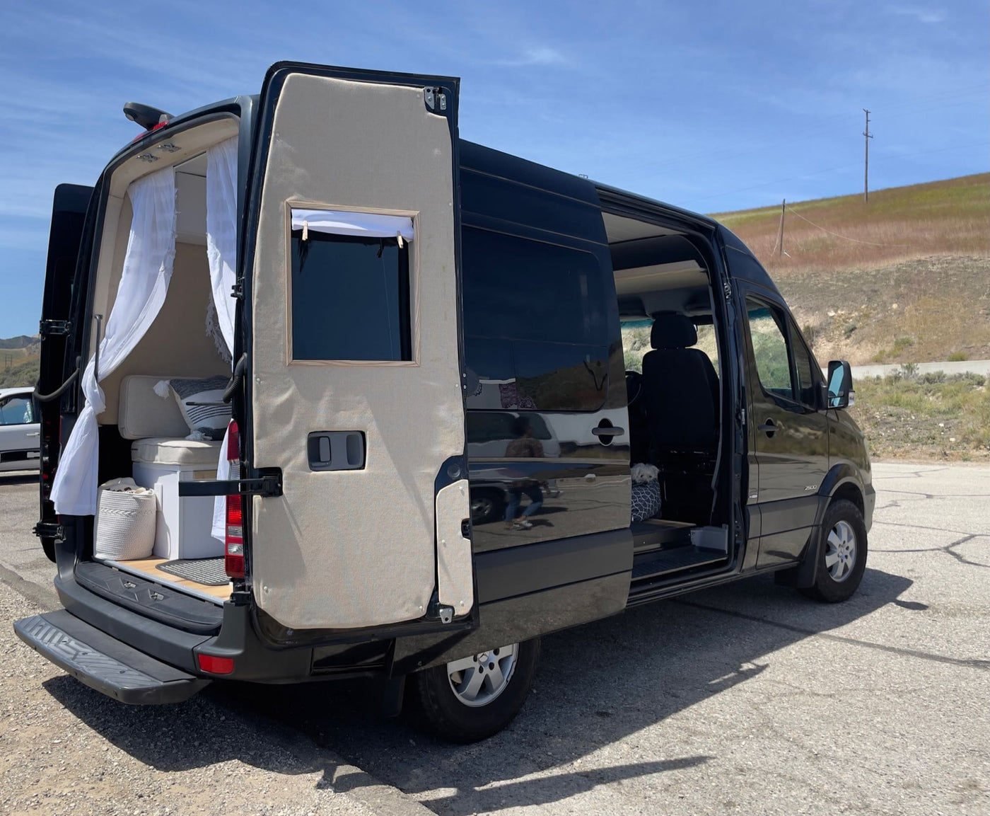 Black Sprinter van converted to an RV, doors open to reveal its cozy interior and a dog. Perfect for an rv rental adventure. — photo 10