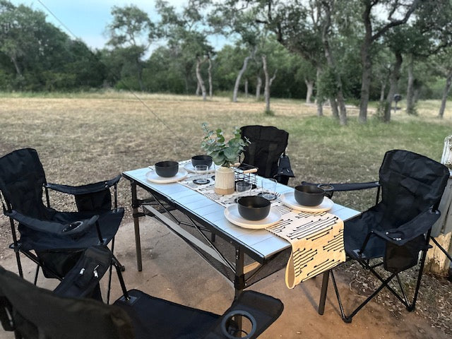 Enjoying an outdoor meal at our RV rental campsite. Portable table and chairs are set for a relaxing dinner amidst nature.