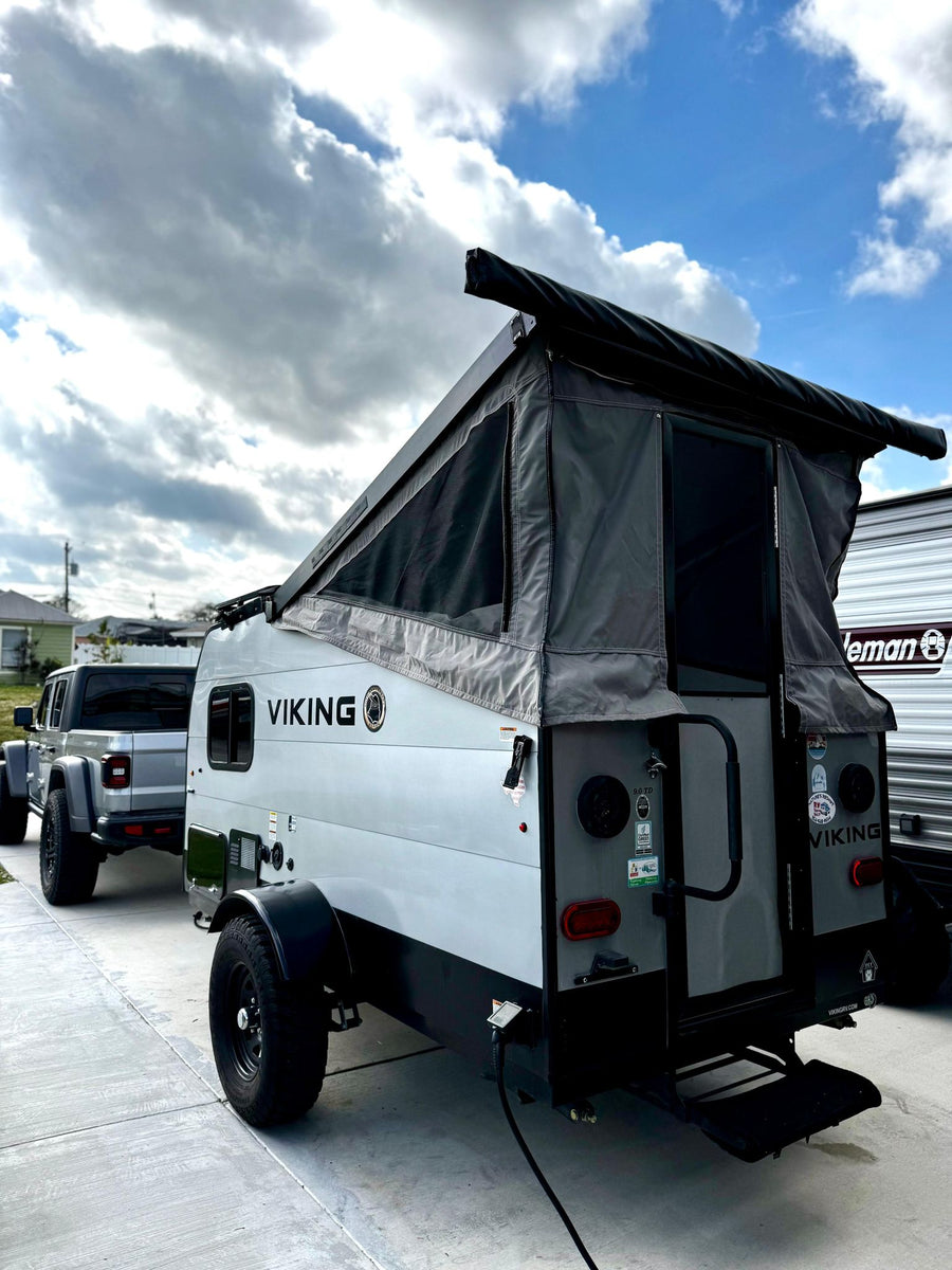 and bag inside.|Modern Arctic King refrigerator and a glimpse of the sleeping area in a spacious RV rental interior.|Front of a Viking travel trailer