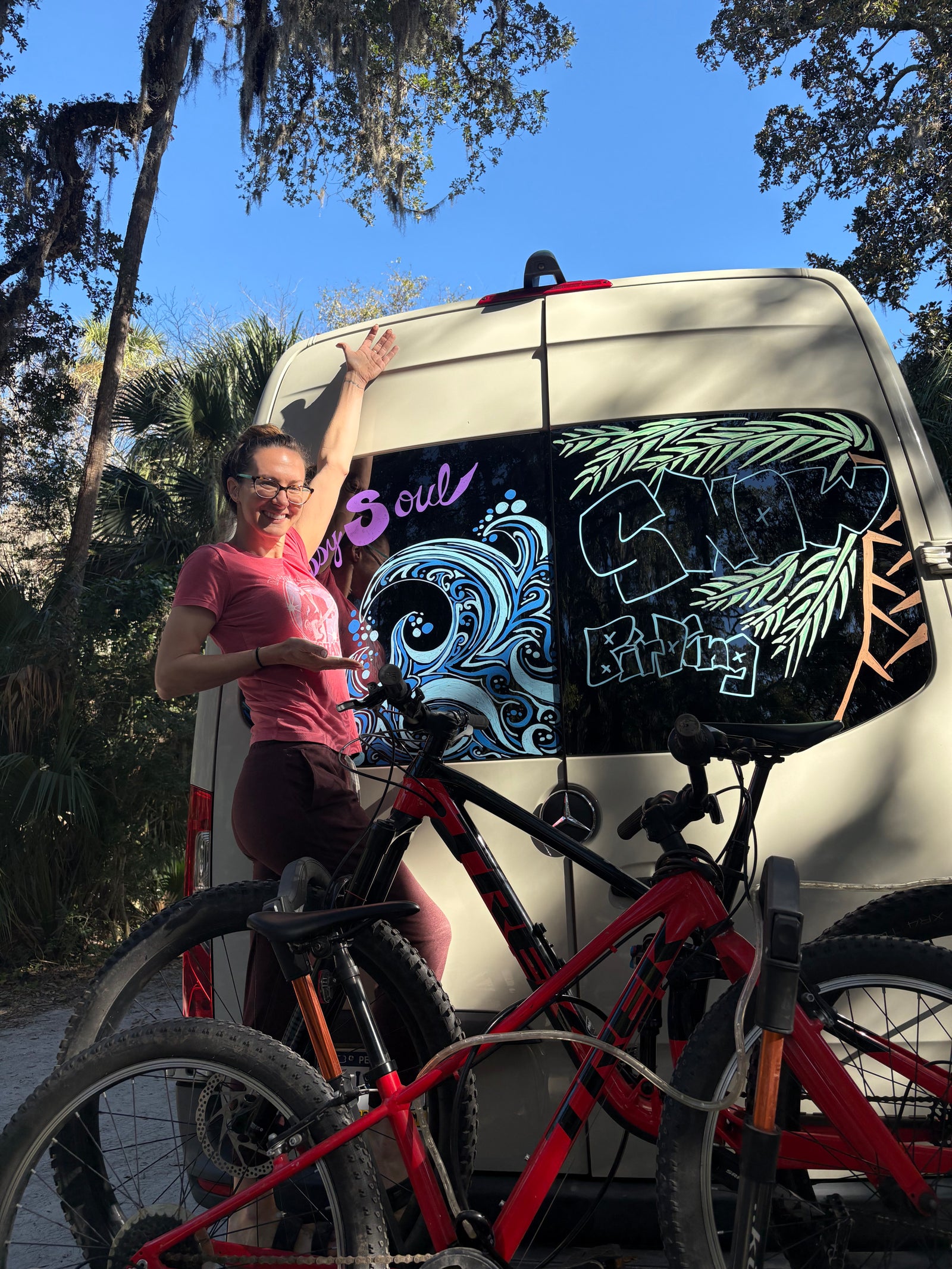 Adventure-ready rv rental with custom window art & mountain bikes, featuring a smiling woman.
