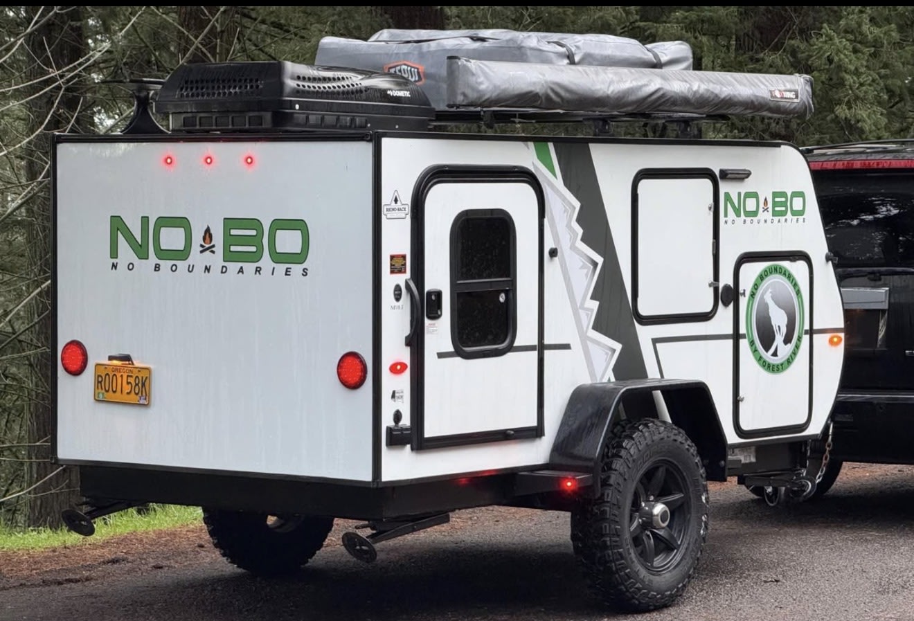 features rugged tires and a rooftop awning.|A NOBO off-road teardrop camping trailer with rooftop tents