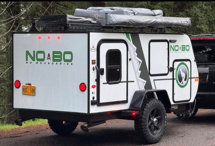 features rugged tires and a rooftop awning.|A NOBO off-road teardrop camping trailer with rooftop tents