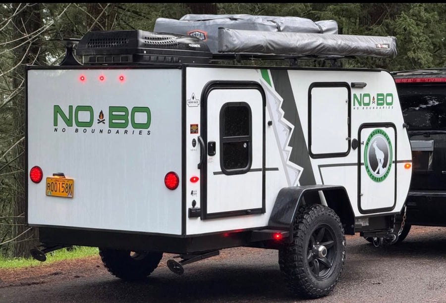 features rugged tires and a rooftop awning.|A NOBO off-road teardrop camping trailer with rooftop tents