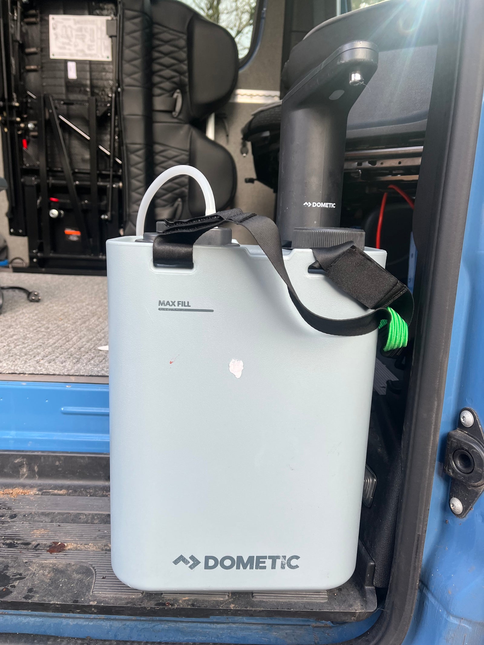 A light gray Dometic portable water container with a black pump inside an RV rental. Great for hydration on trips.