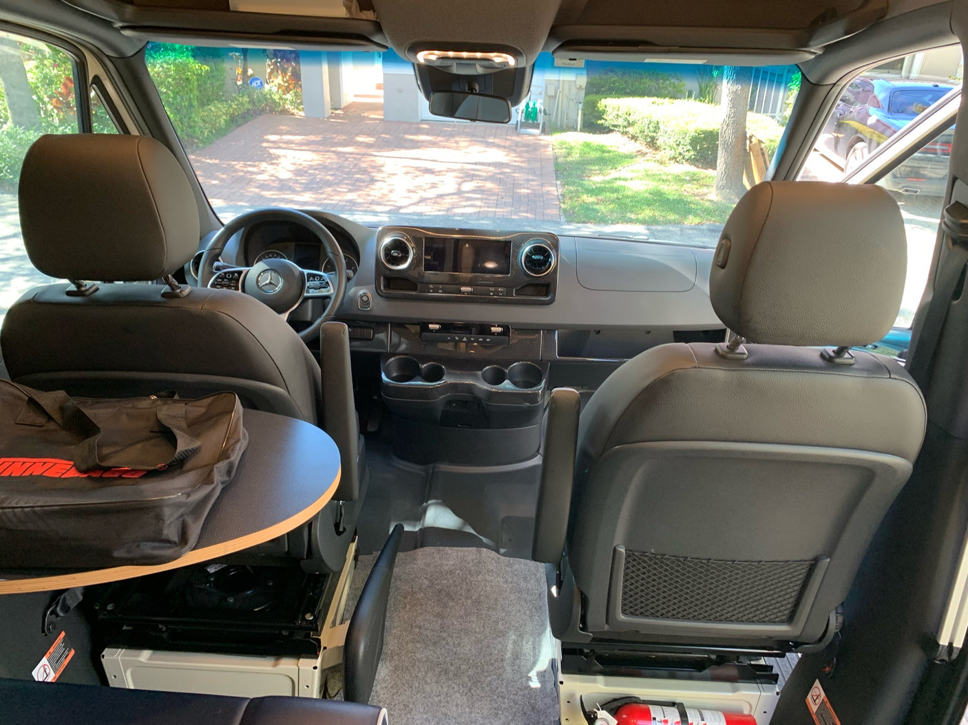 RV rental: Camper van interior. Front cabin with swivel captain's chairs, portable table, dash, and clear road view.