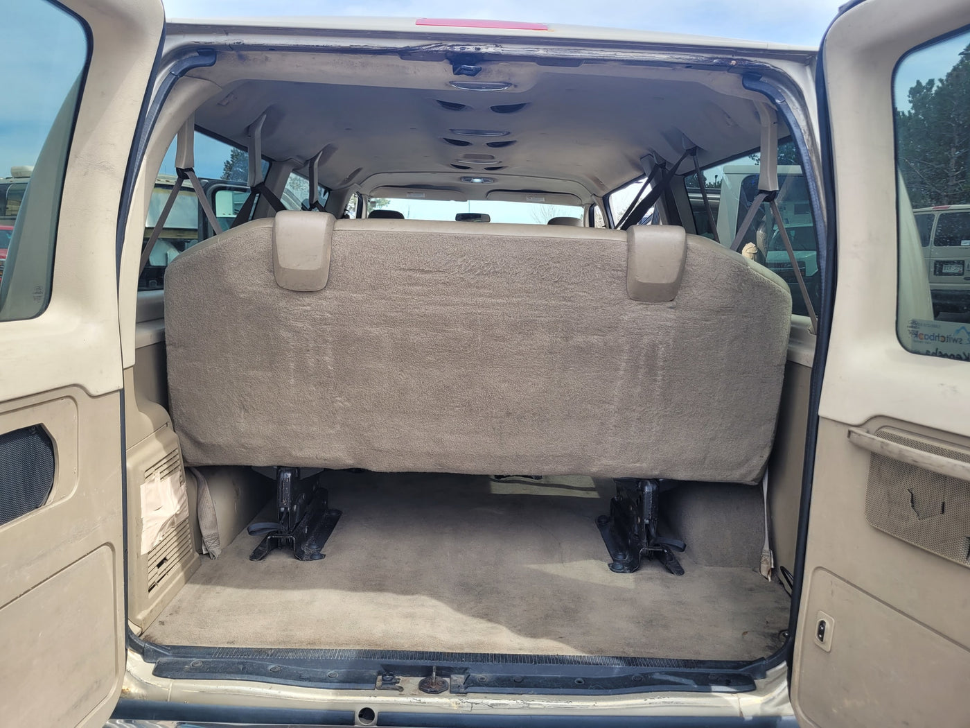 RV rental: Rear view inside a spacious passenger van, featuring the large bench seat & carpeted cargo area. — photo 7