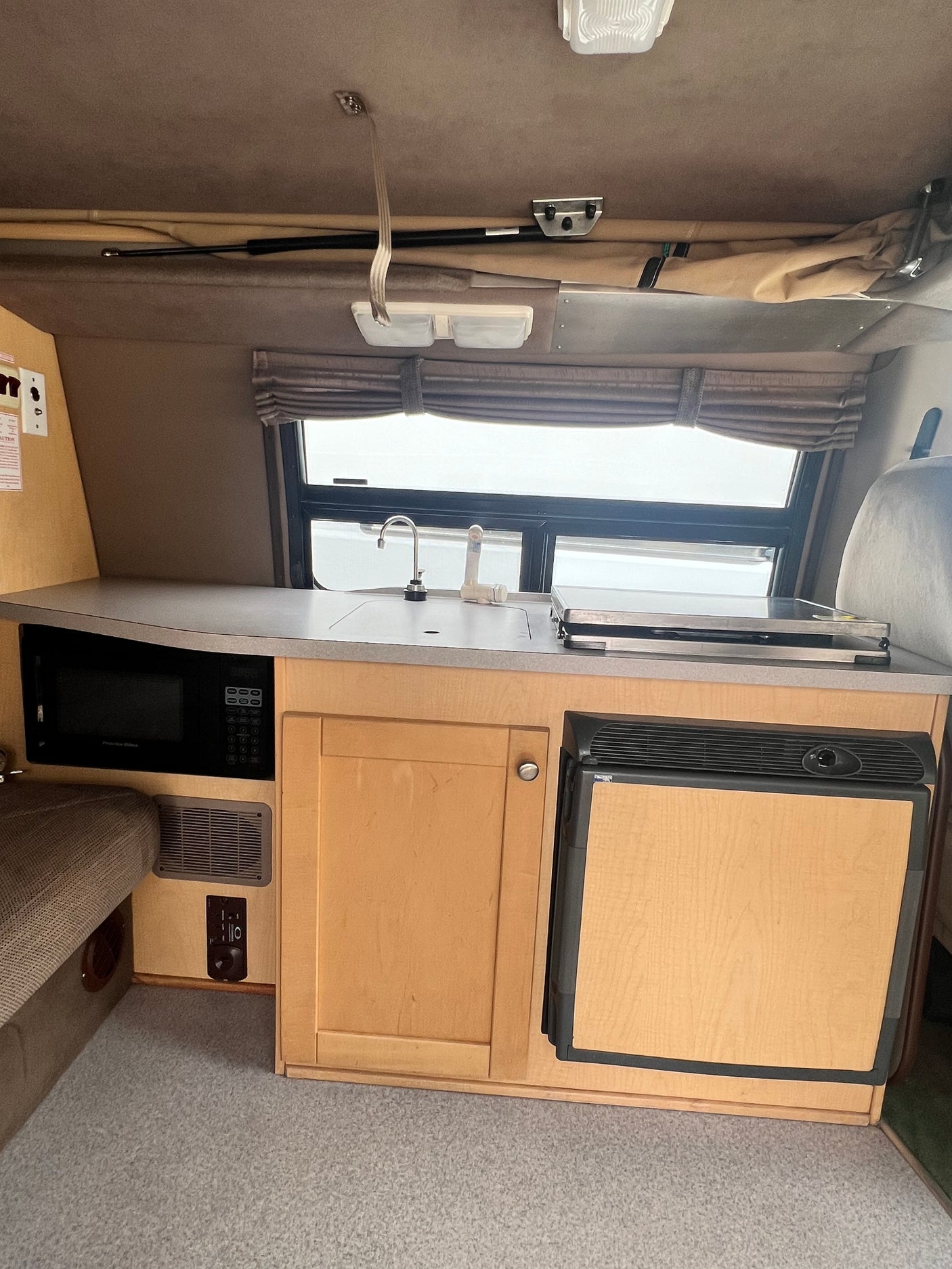 Well-equipped RV rental galley kitchen with microwave, refrigerator, sink, and stovetop, perfect for on-the-go meals.