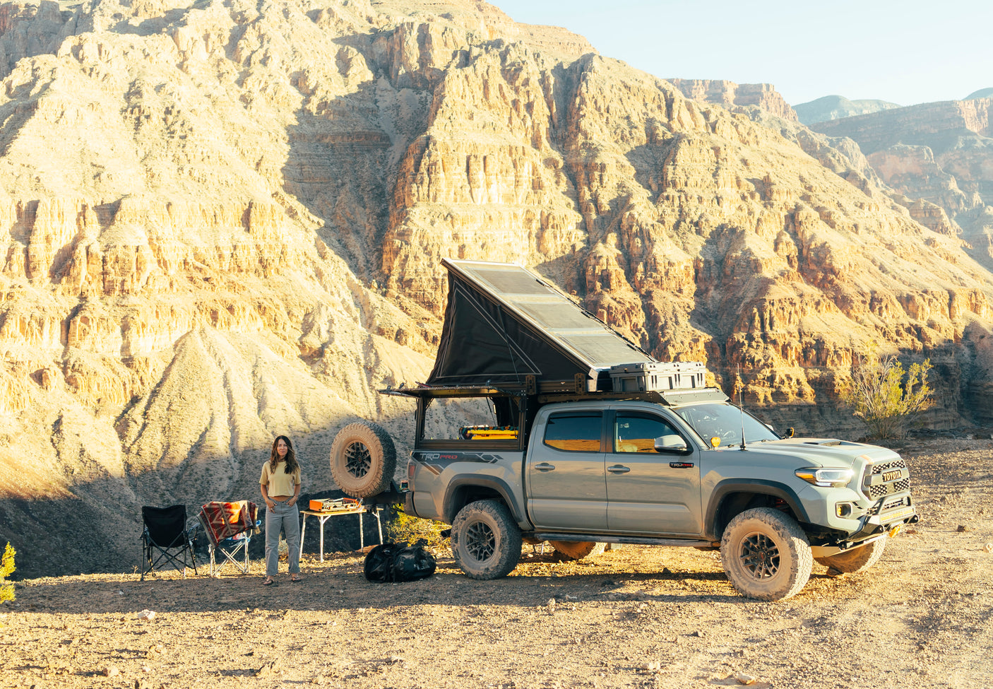 Woman by her overlanding Toyota Tacoma truck camper, a perfect RV rental for desert mountain adventures.