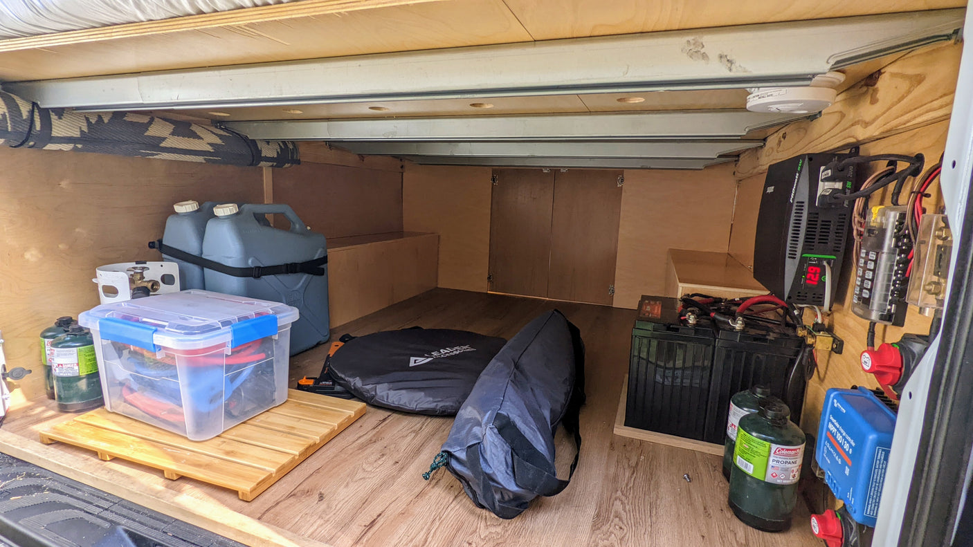 Inside an RV rental: organized under-bed storage with water, propane, gear, and a robust off-grid power system.