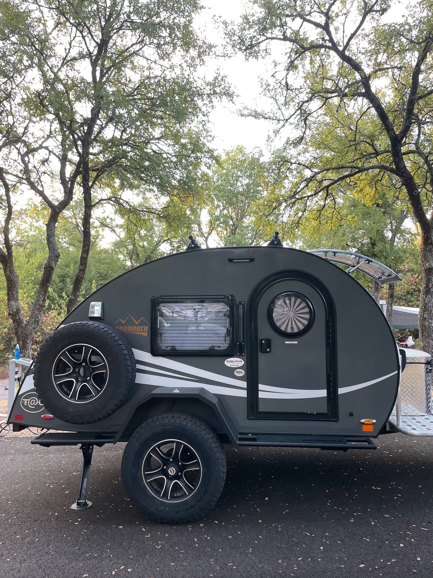 and green foliage above a blue bed.|This rv rental offers a compact teardrop camper kitchen! Features sink