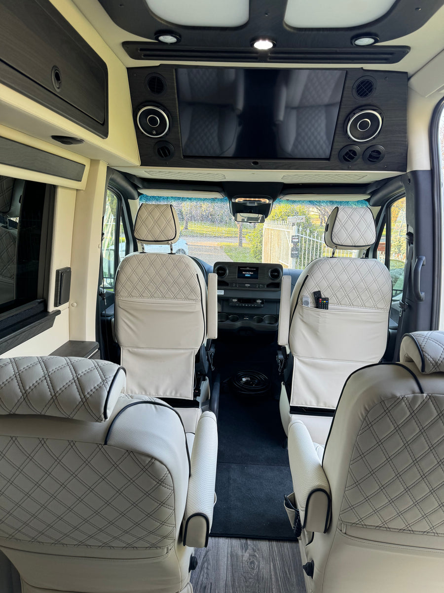 Luxurious RV rental interior, showing cream diamond-quilted seats, front dashboard, and entertainment system.