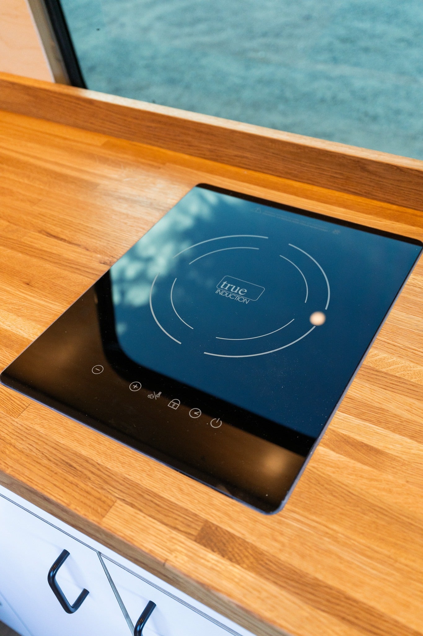 Enjoy home cooking in your RV rental with this sleek, built-in induction cooktop on a modern wooden counter.
