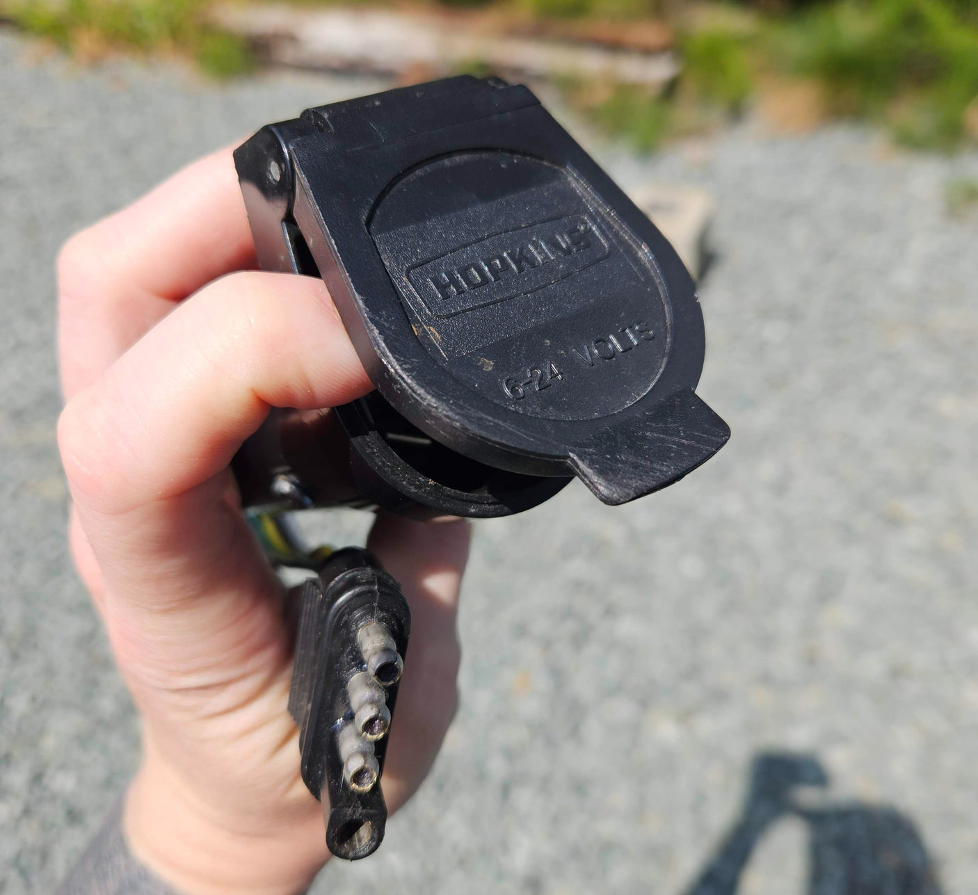 Close-up of a Hopkins 4-pin trailer electrical connector (6-24V) for RV rental hookup.