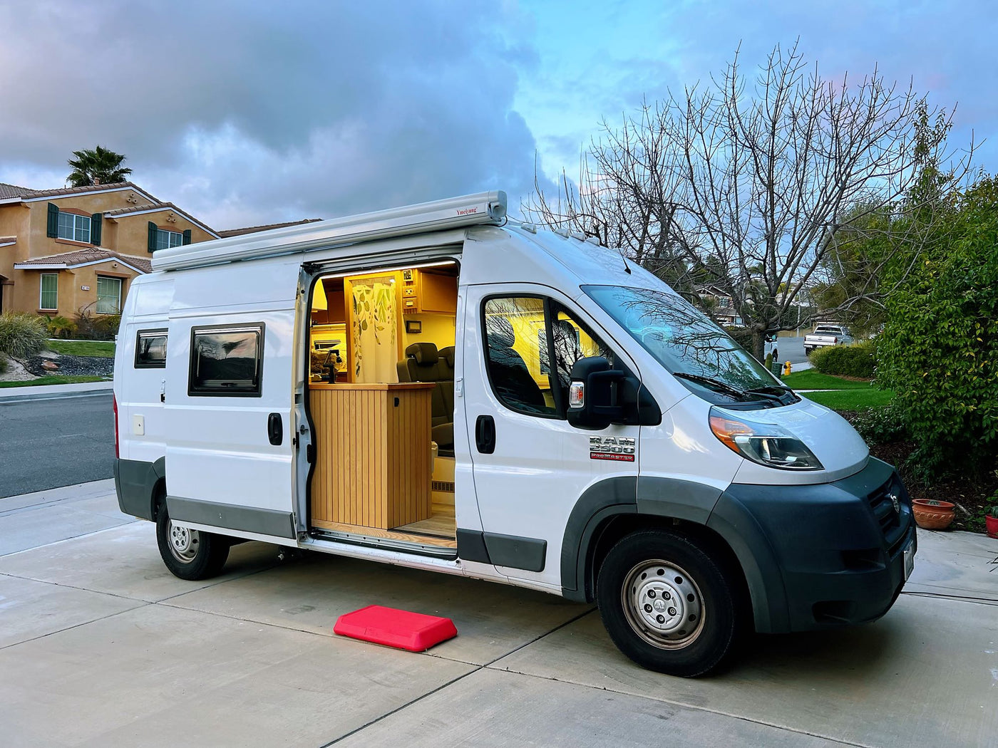 White Ram ProMaster **rv rental** van conversion with lit interior and extended awning — photo 1