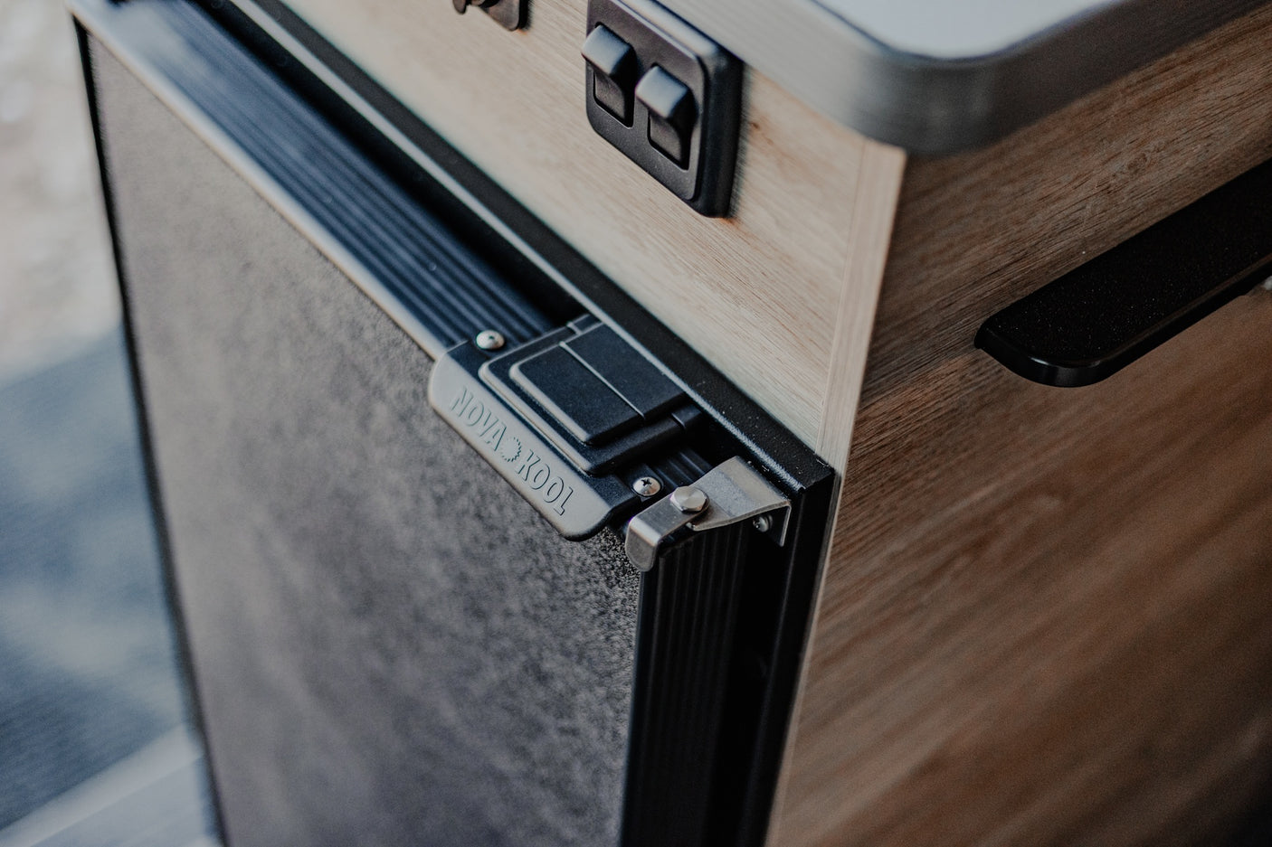Nova Kool fridge door latch and switches integrated into a light wood cabinet, perfect for your RV rental.
