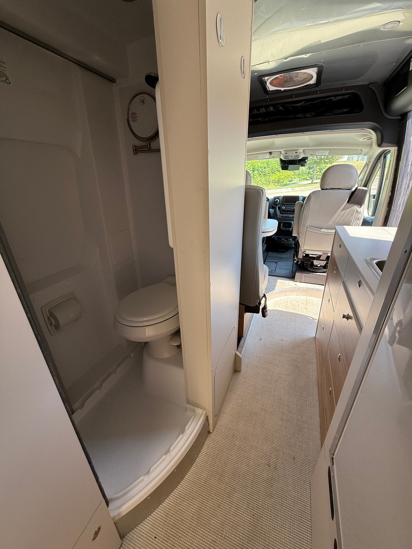 and rear opening to trees. Features a compact kitchen.|Experience a comfortable RV rental. View of a modern van's spacious cockpit with dashboard
