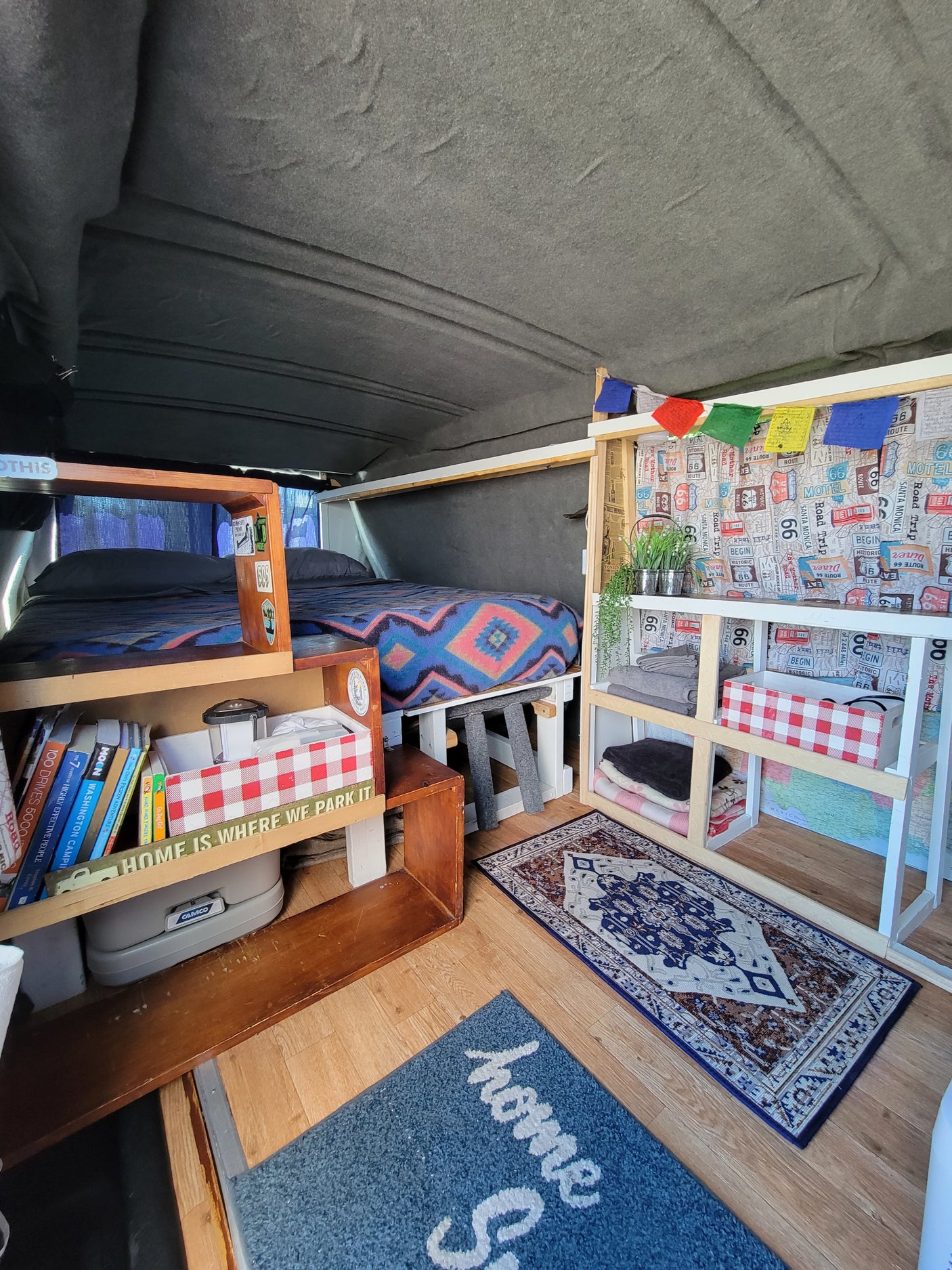 Cozy **RV rental** interior, showing a neat bed, organized shelving, and a **portable toilet**. It's a well-equipped **camper van** space.