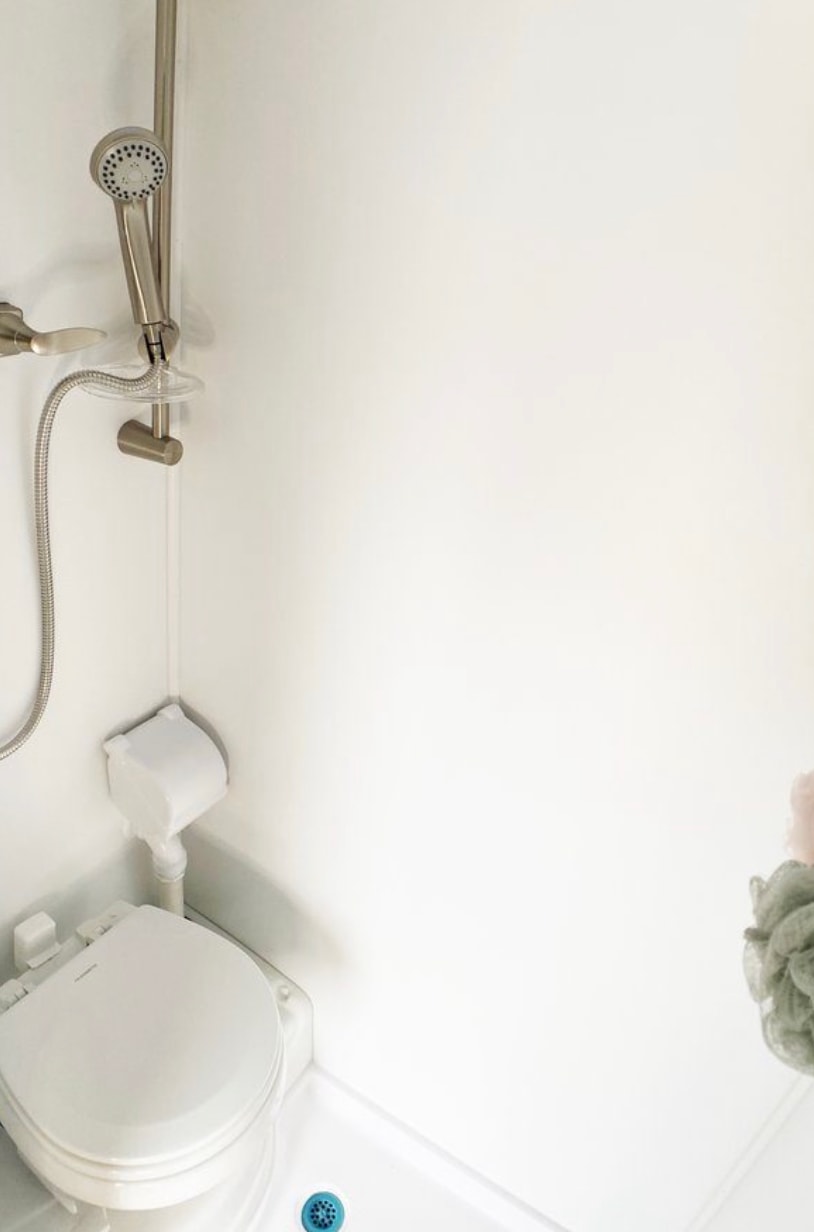 Experience comfort in this RV rental bathroom, featuring a white toilet, handheld shower, and floor drain.