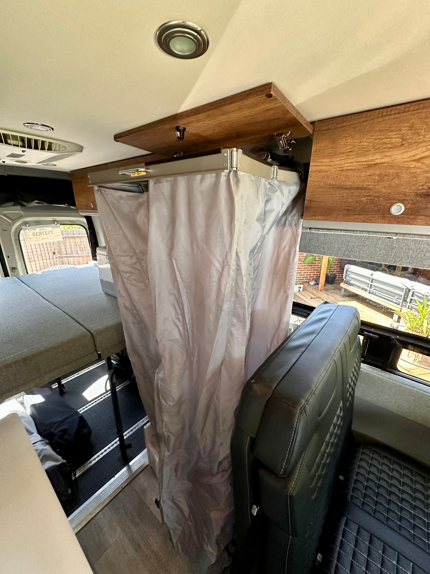 RV rental interior showcasing a collapsible shower, modular bed, and comfortable seating in a versatile camper van.