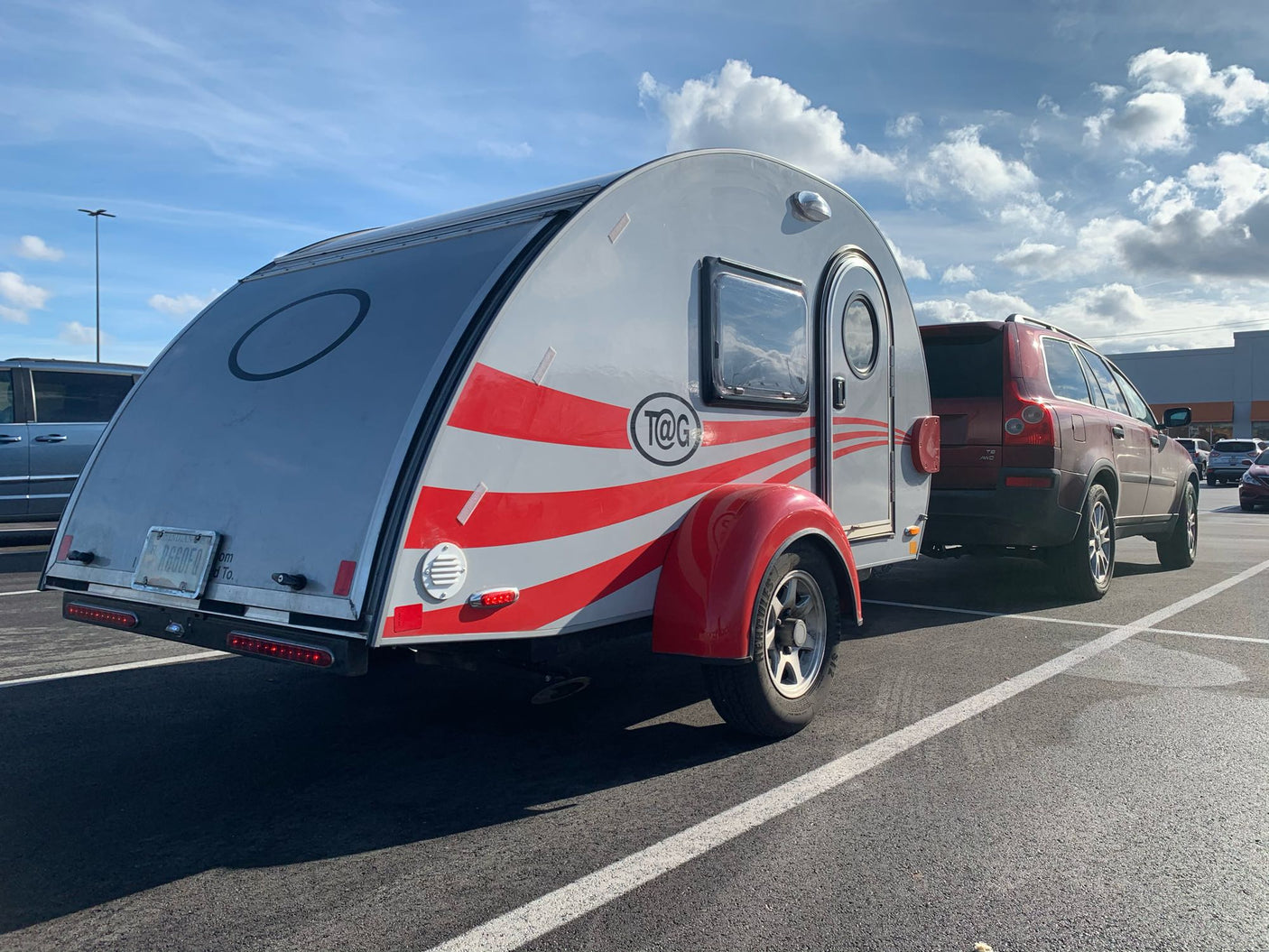 A silver T@G teardrop RV with red stripes