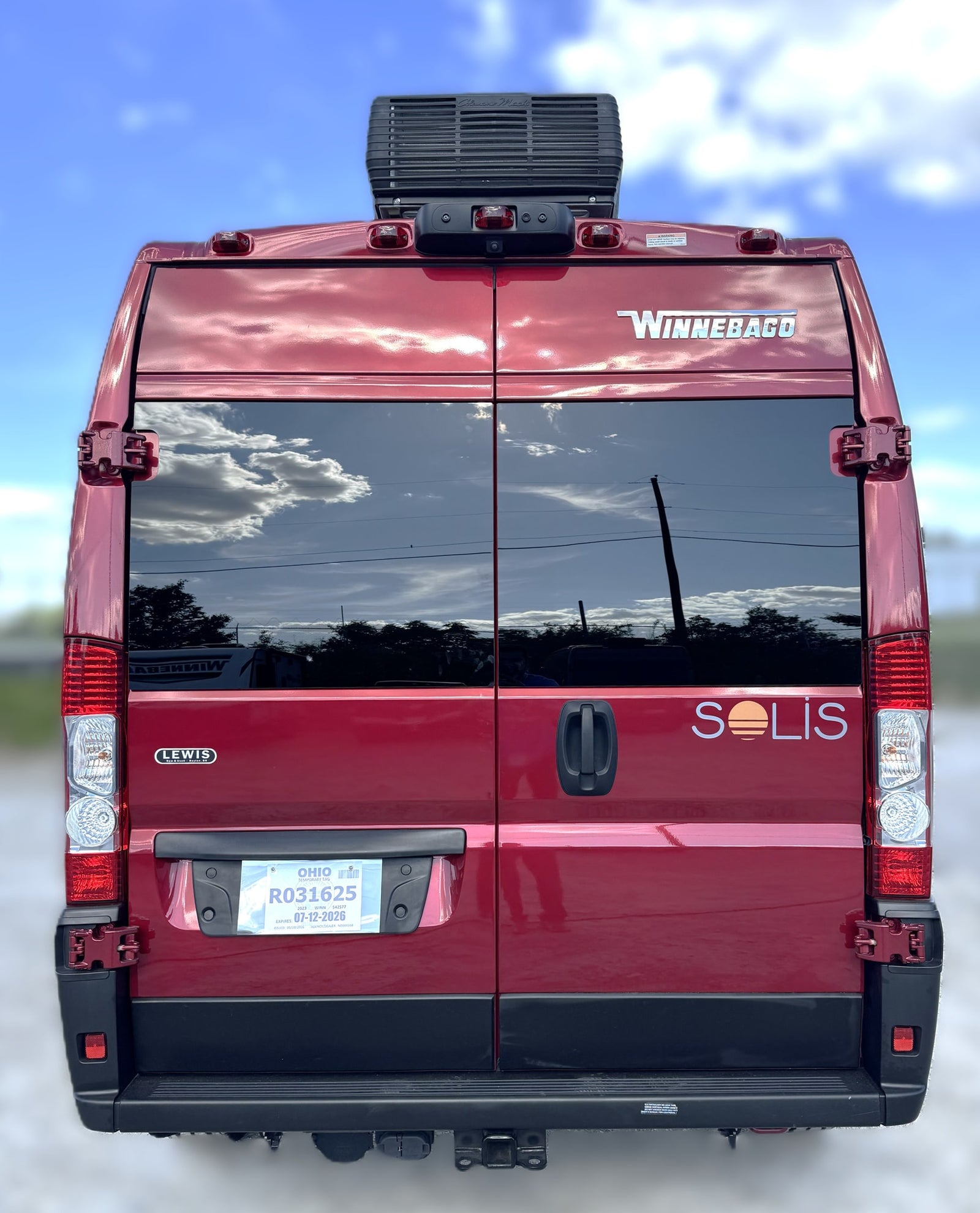Rear view of a red Winnebago Solis camper van, with Ohio temporary tag and AC unit visible. Ideal for rv rental.