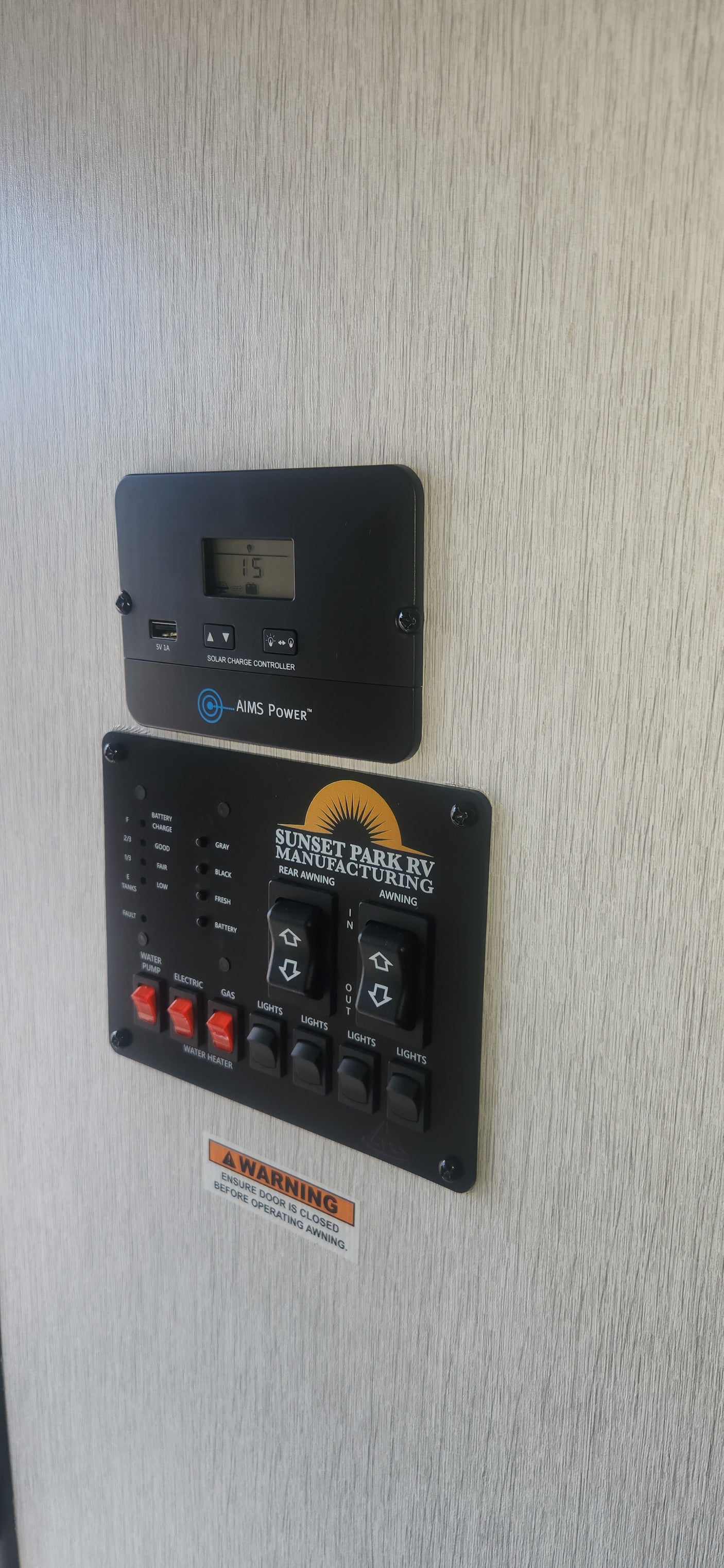 RV rental's interior control panel: monitoring battery/tanks, managing water, lights, and awnings, with solar charger display.