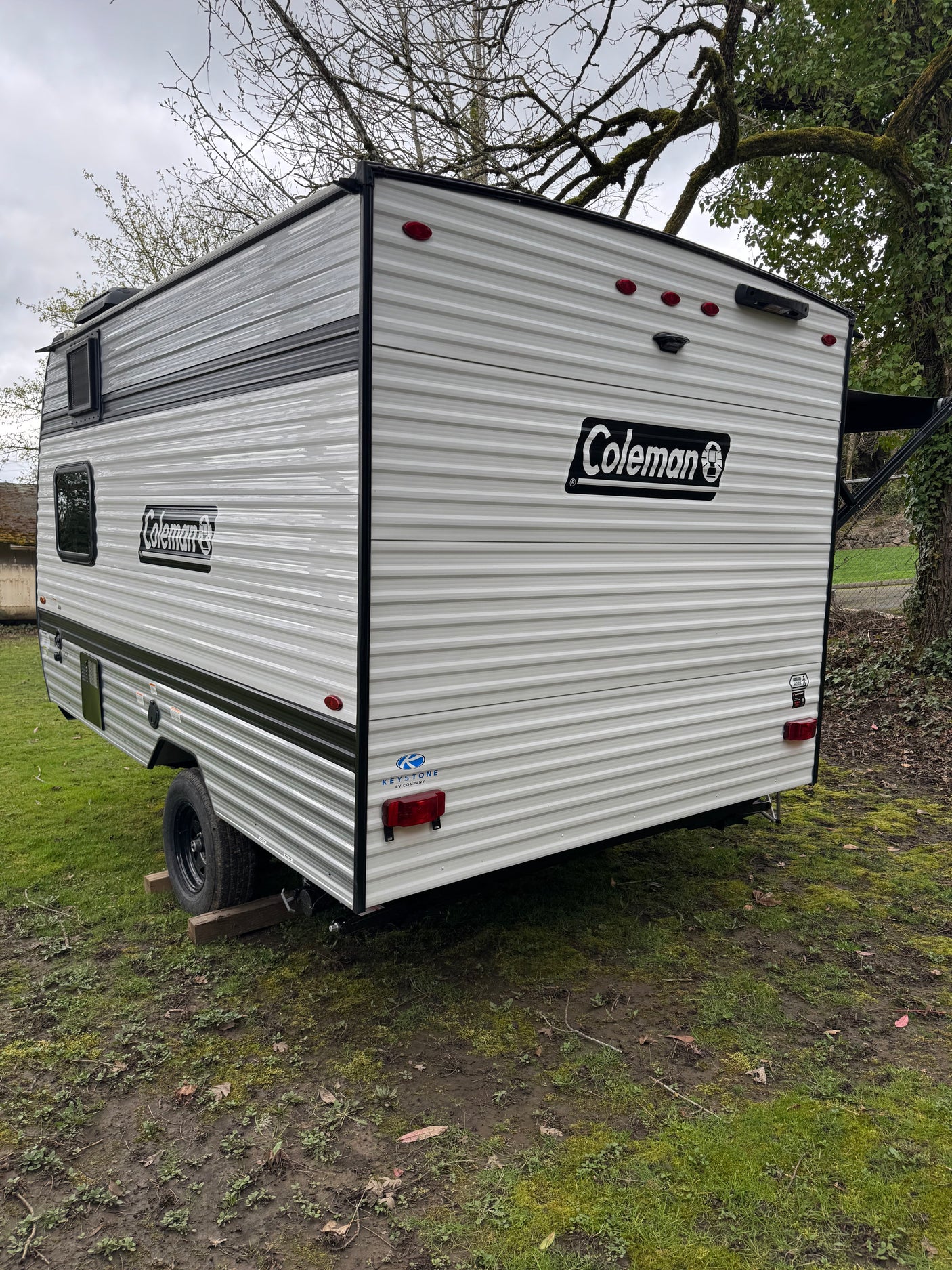 Explore this Coleman travel trailer, ideal for an RV rental adventure. The spacious camper is shown parked on a grassy outdoor area.