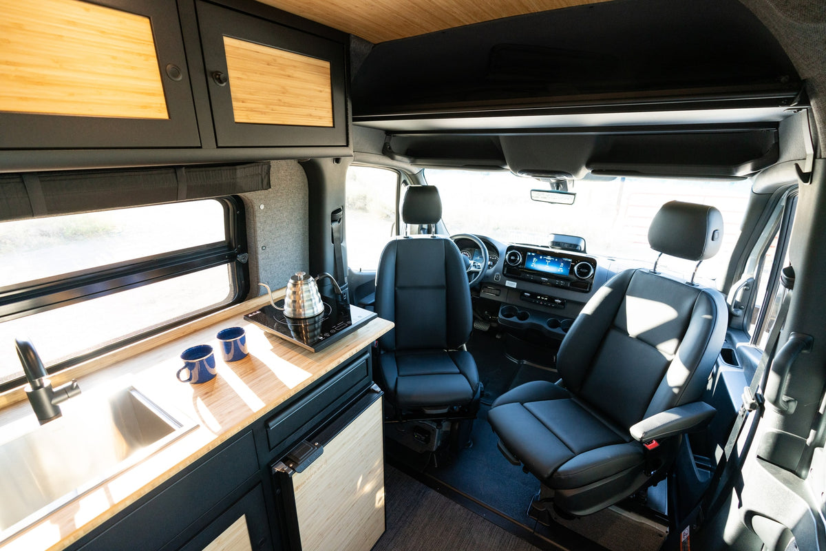 Modern RV rental interior: kitchen with sink, cooktop, and comfy swivel seats upfront. Ready for your next adventure. — photo 20
