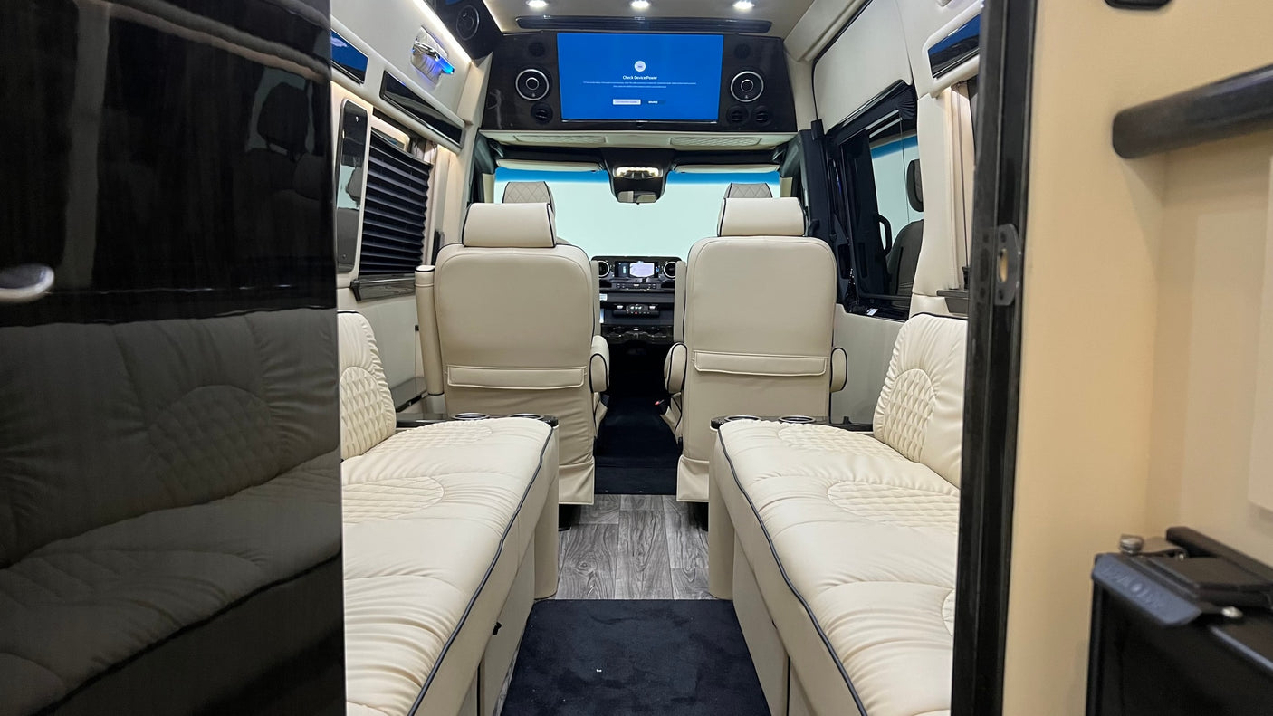 Step inside this modern rv rental, featuring luxurious cream seating, wood-look floor, and an overhead entertainment screen.