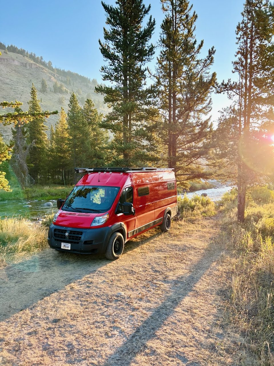 Red RV rental parked by a river