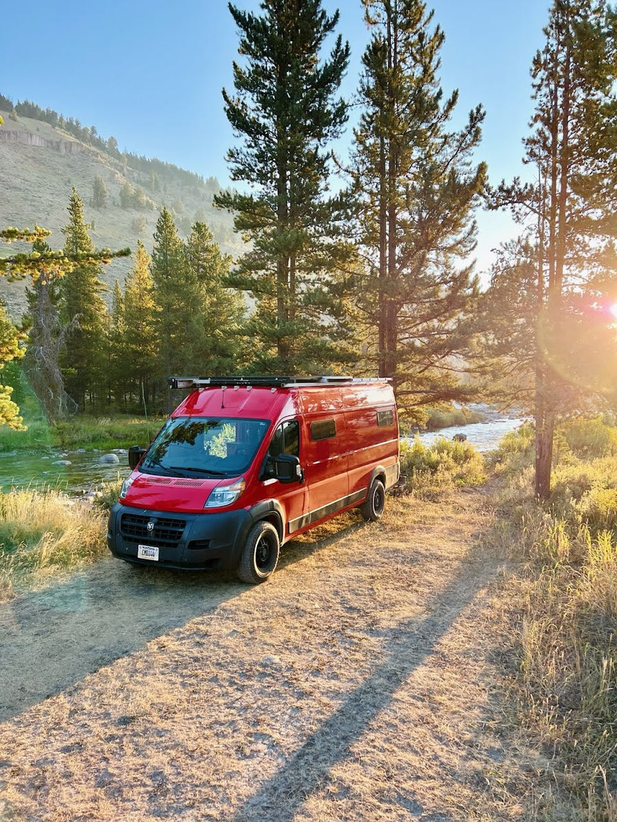 Red RV rental parked by a river