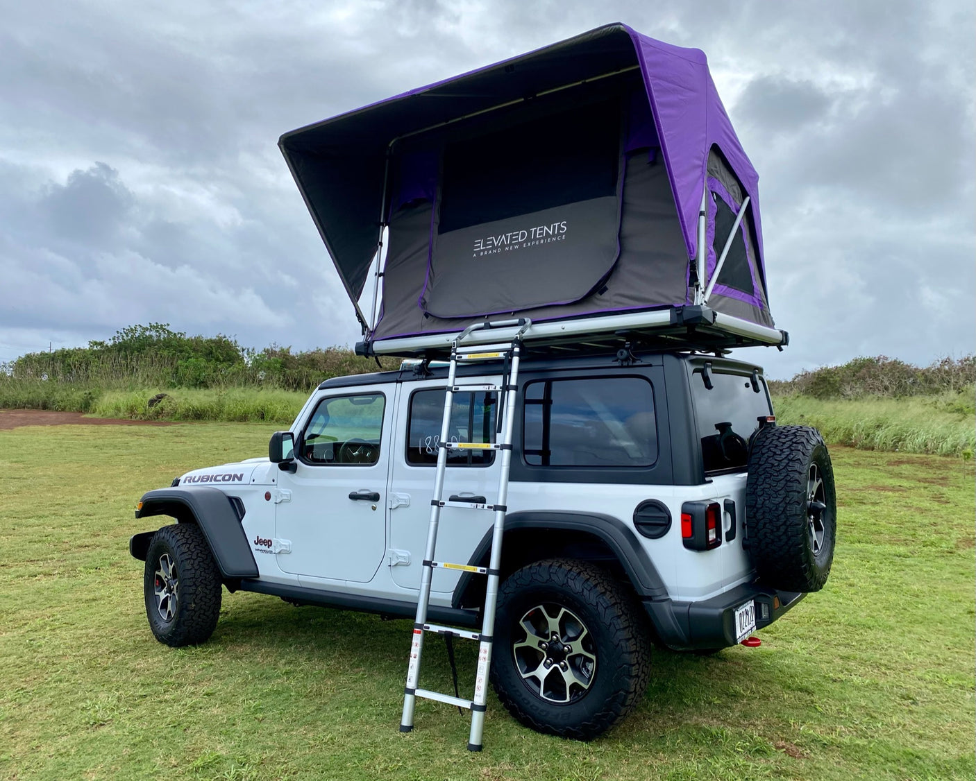 This white Jeep Wrangler, with a purple Elevated Tents roof top tent and ladder, is ideal for an overland RV rental camping trip.