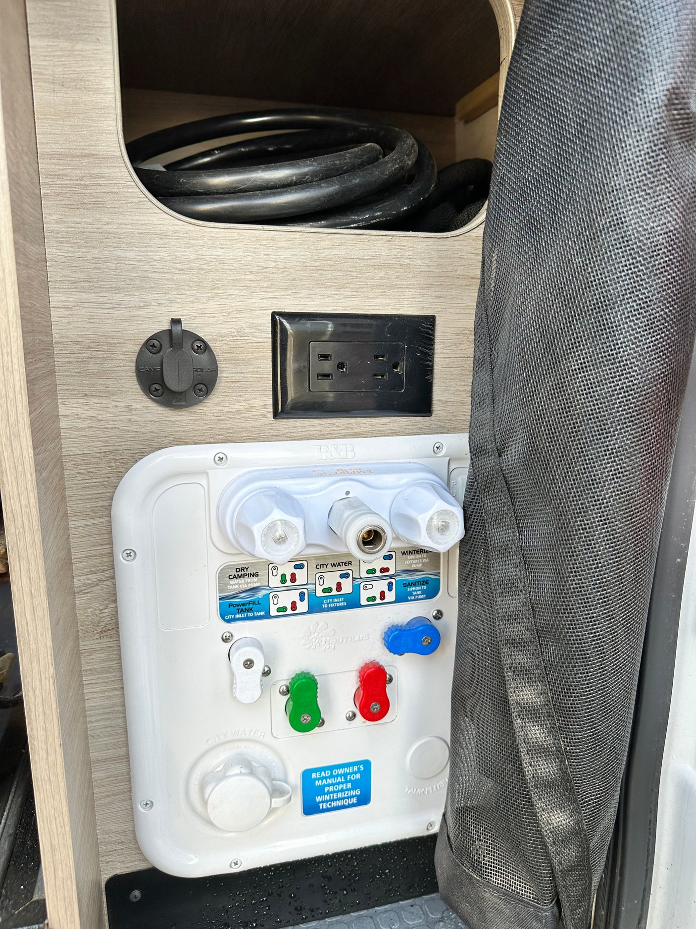 RV rental utility panel: Nautilus P3 water controls, AC outlet, and Zamp solar port for seamless camping.