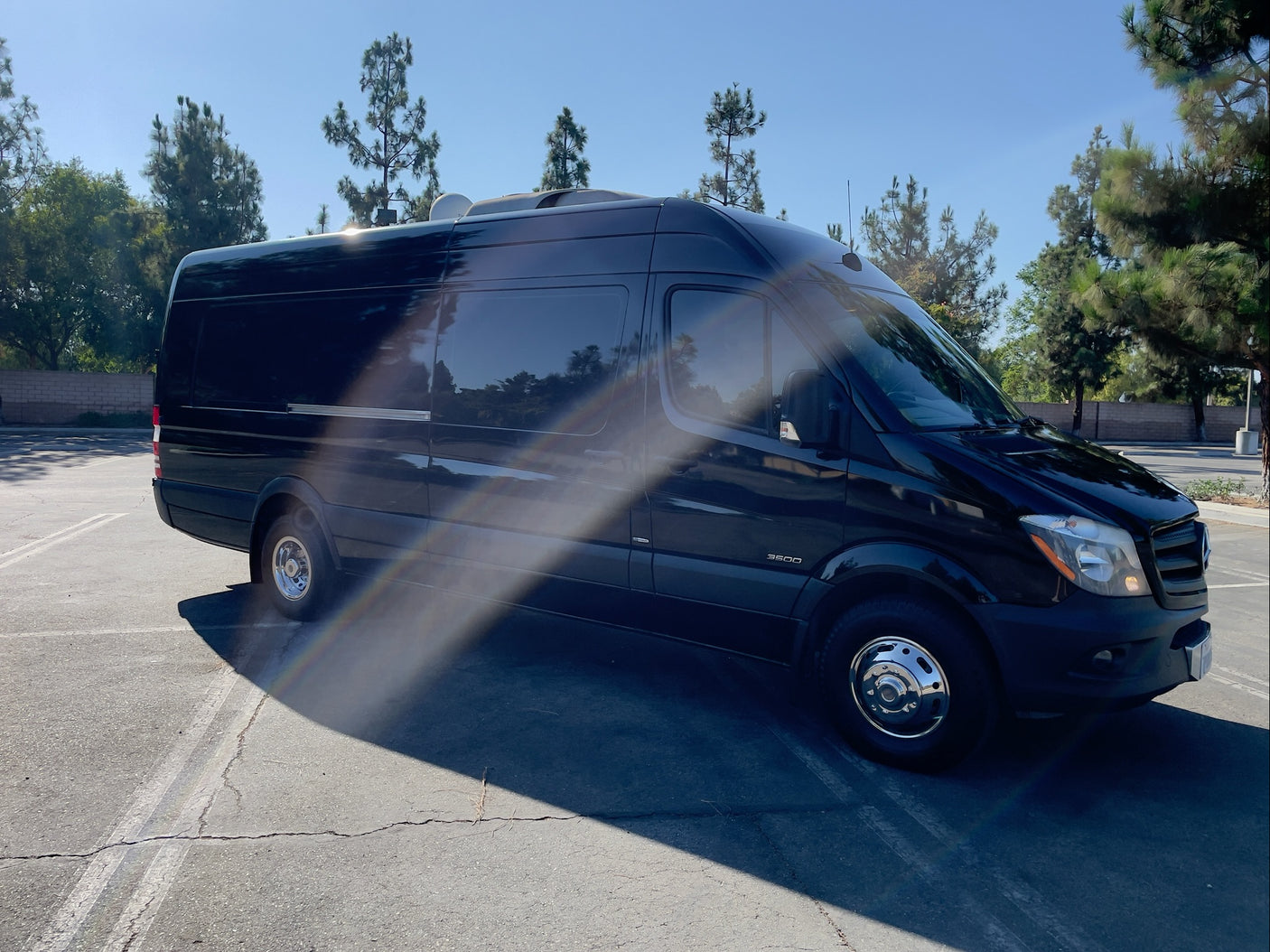 Black Mercedes-Benz Sprinter van, perfect for your next RV rental adventure. Parked on asphalt under sunny skies.